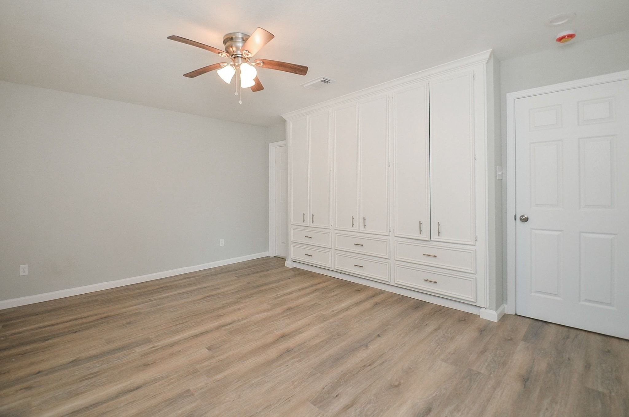 Built-in wardrobe adds the perfect flare to this expansive room. Crisp cabinetry and storage space, and off-white walls, gorgeous and easy-to-maintain wood-like flooring.