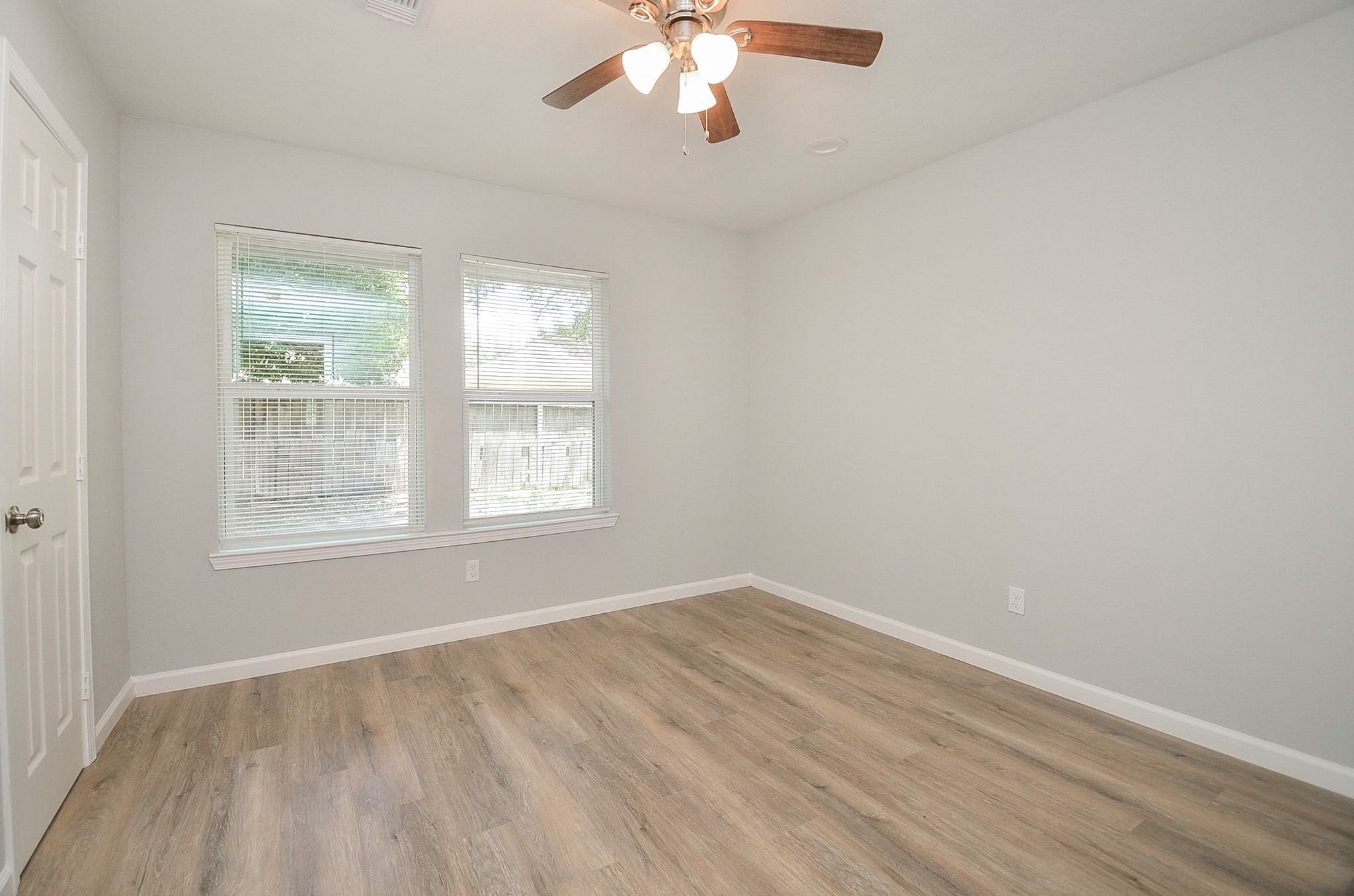 Discover the first bedroom that provides neutral walls, a ceiling fan for comfort year-round, and huge windows.