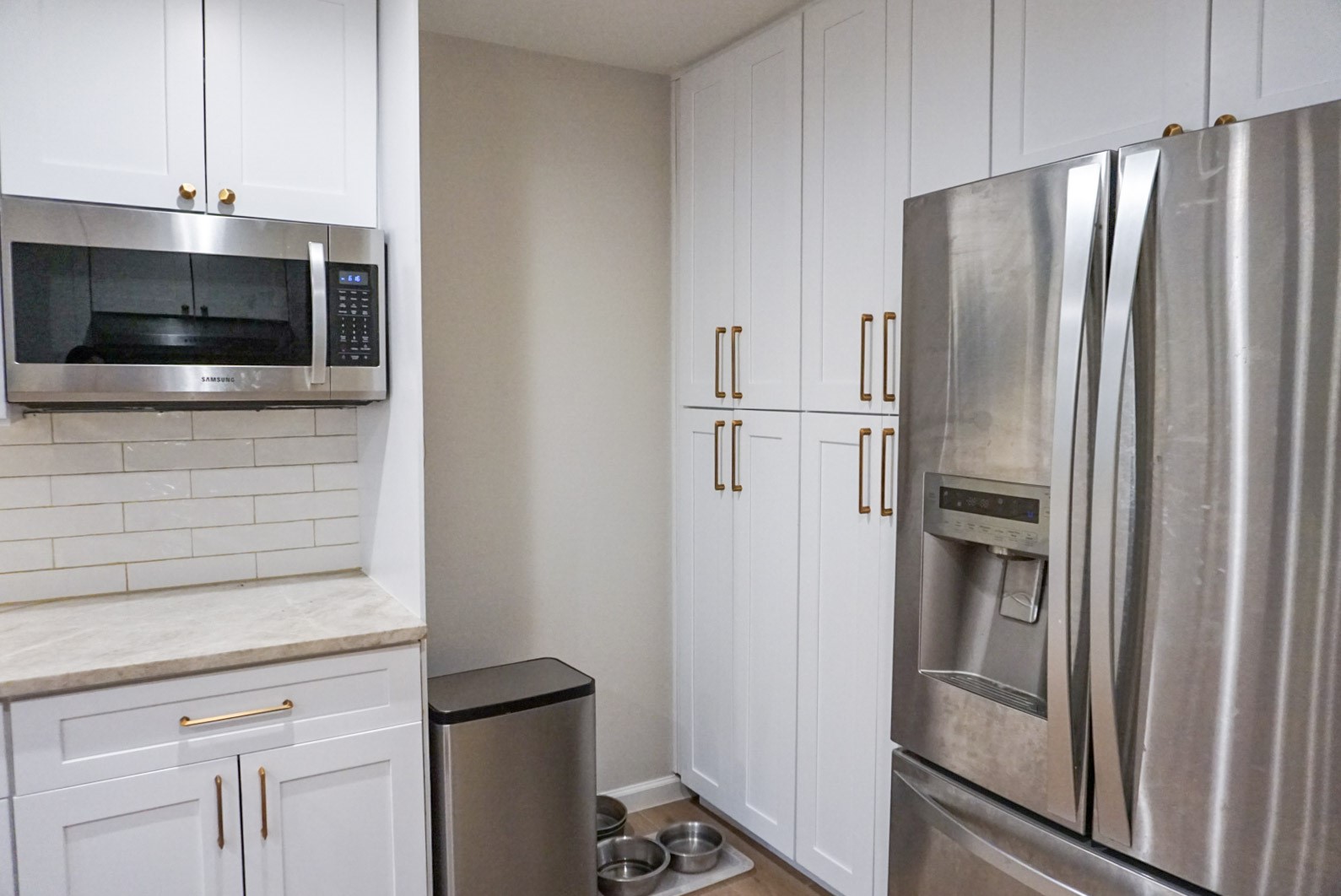 Thoughtful nook design at end of kitchen in front of pantry for garbage, recycle, and pet bowls