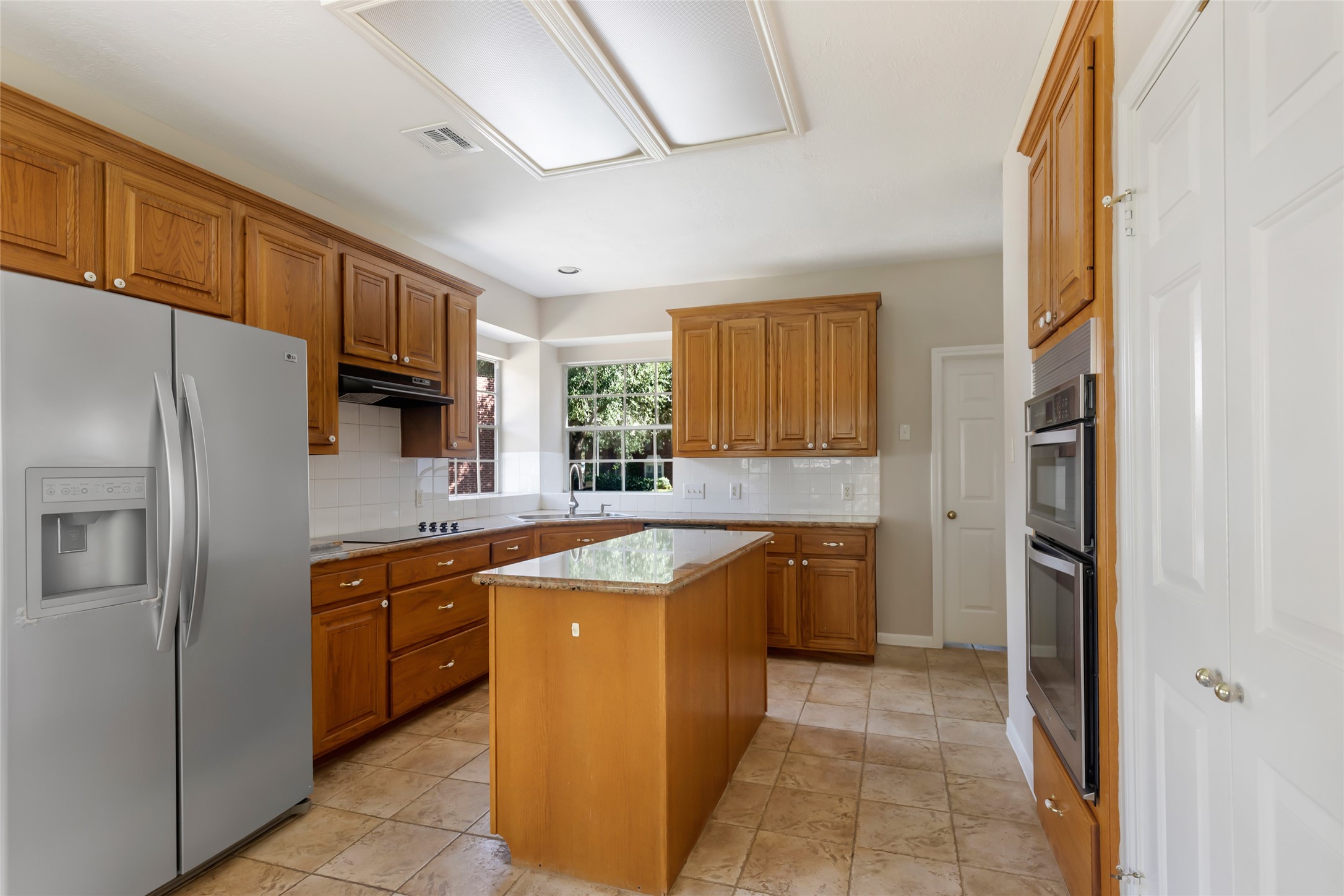 Custom warm stained wood cabinets with island. Refrigerator is included.