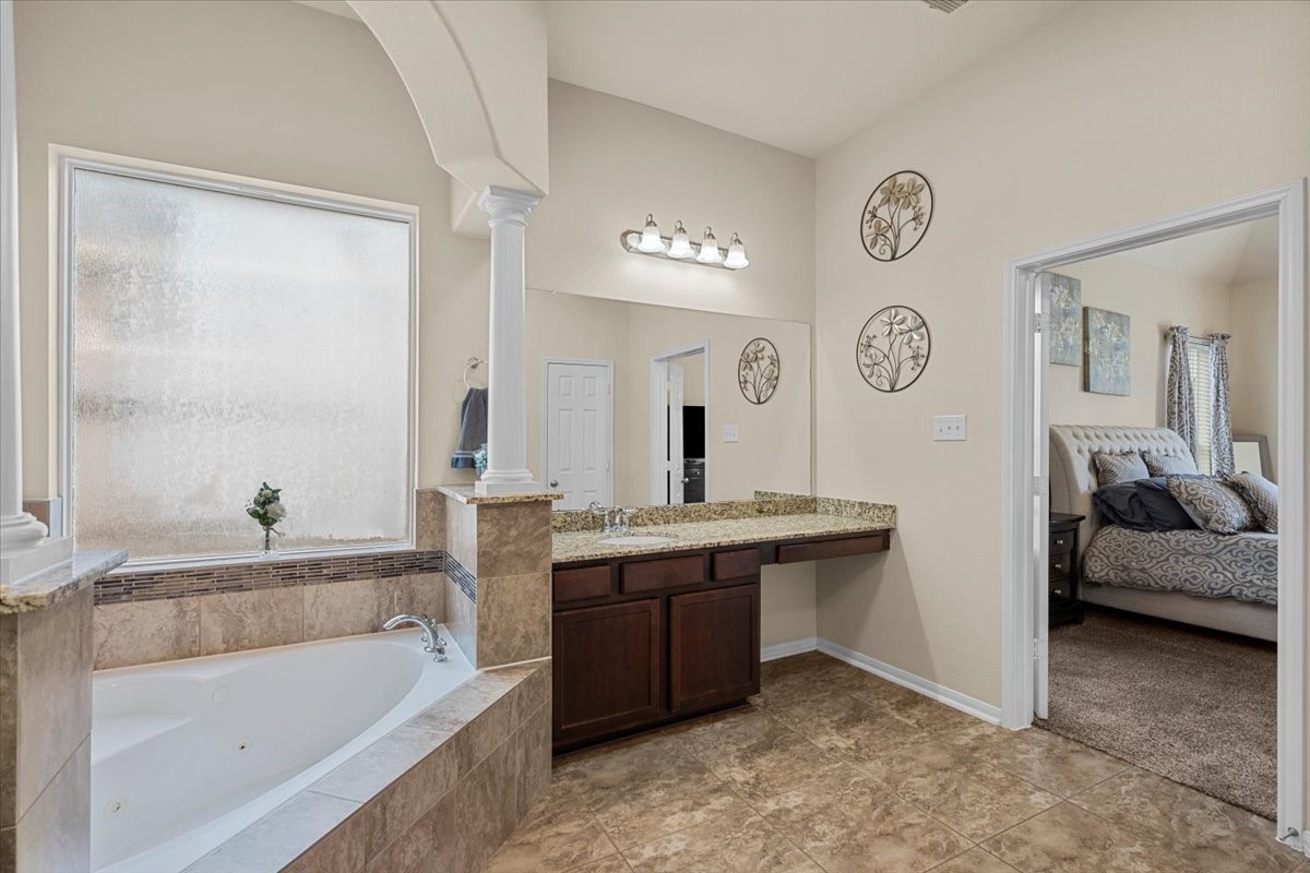 Primary bath with soaking tub, vanity, and direct access to the bedroom.