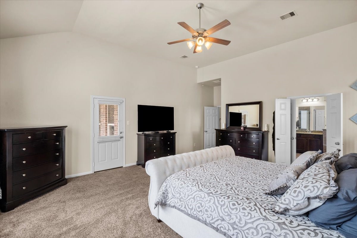 Another angle of the primary bedroom with ceiling fan and soft carpet.