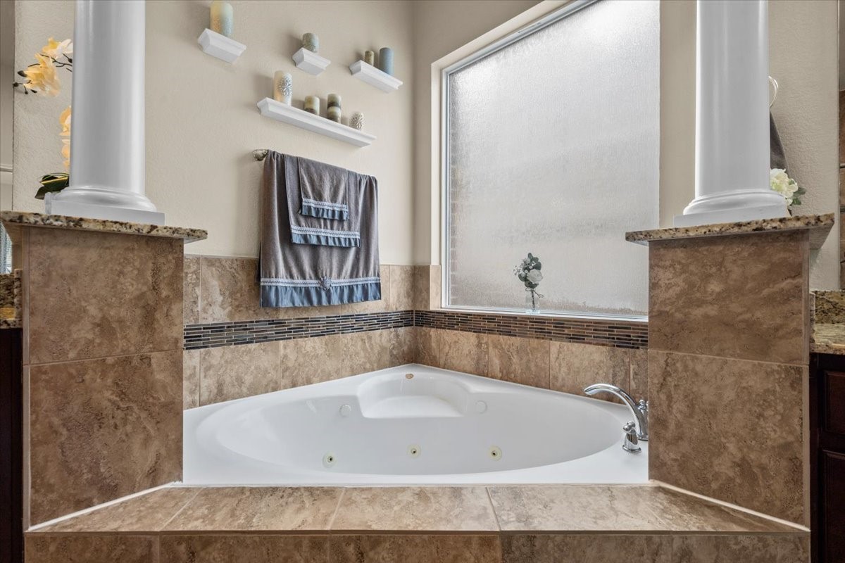 Corner soaking tub framed by columns for a spa-like retreat.