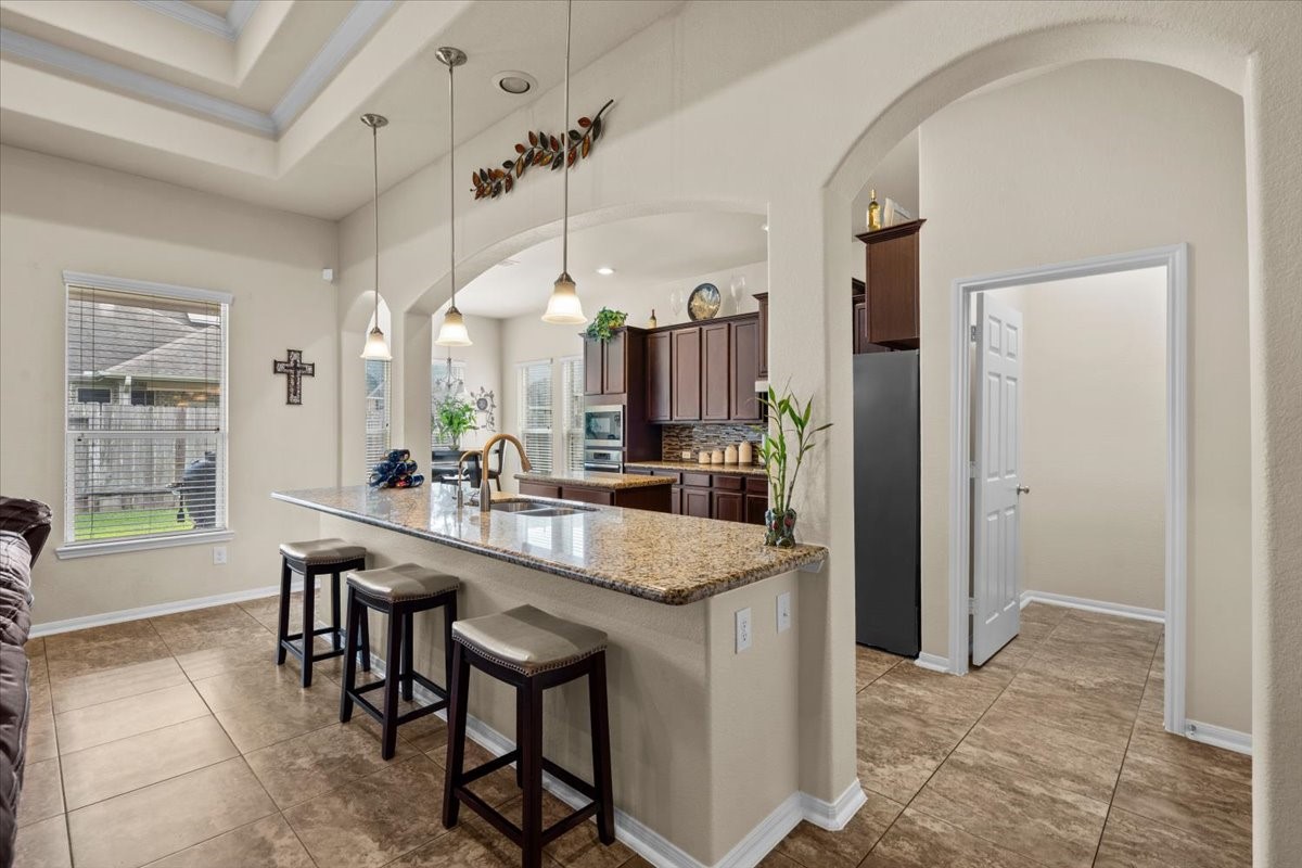Kitchen with breakfast bar seating and graceful arched details.