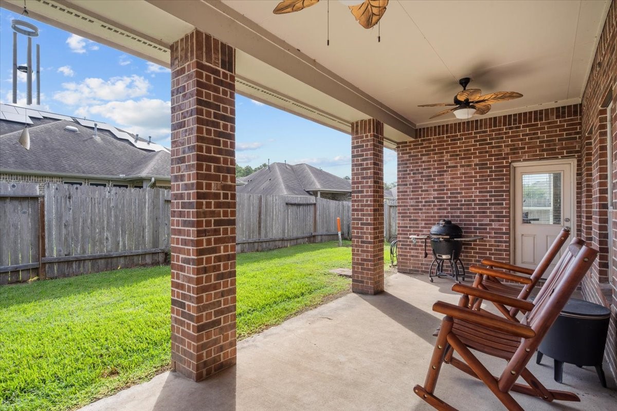 Covered patio with ceiling fans overlooking the fenced backyard.