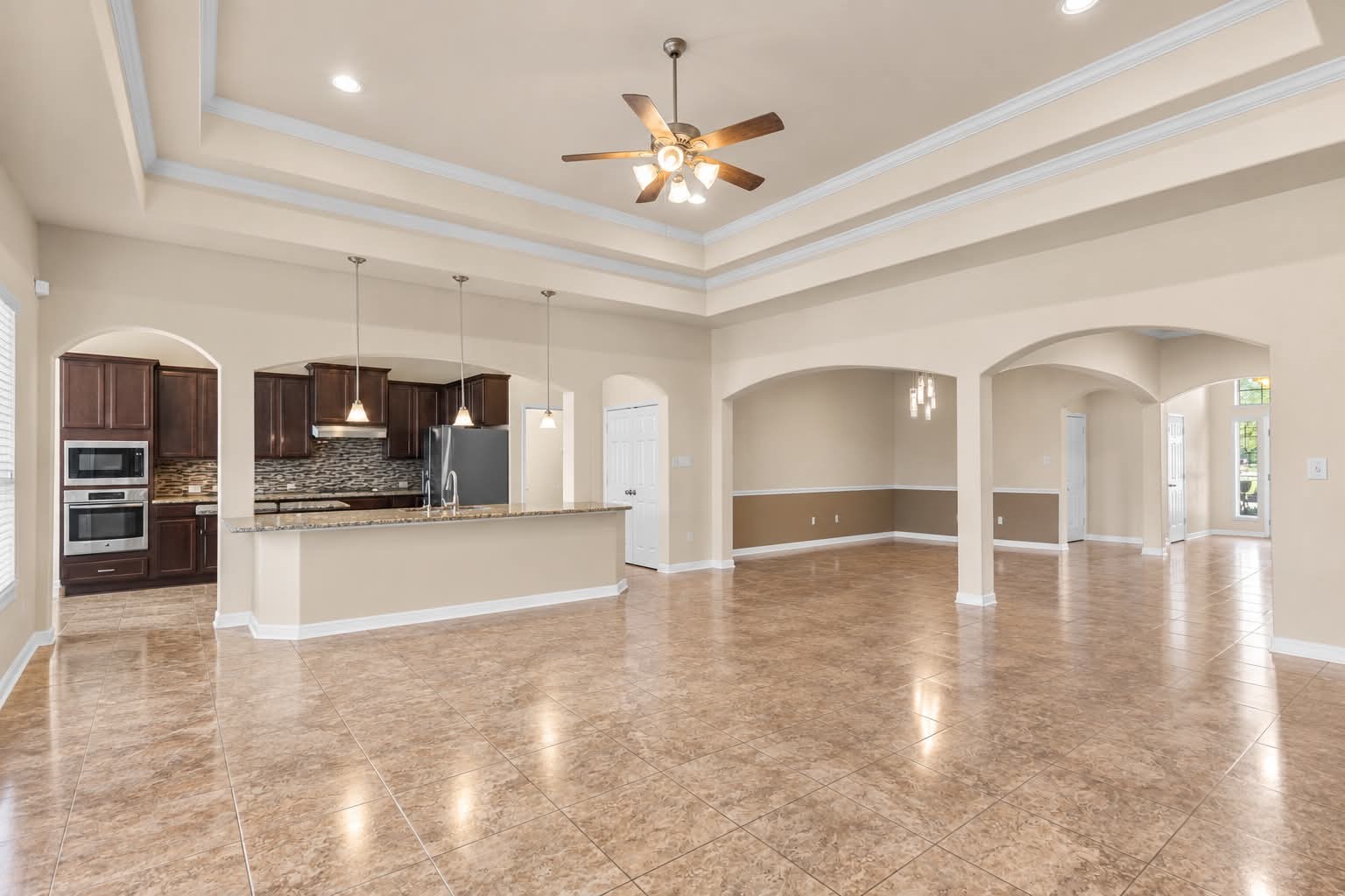 Open living space with arched openings connecting to the kitchen and dining areas. Open living space with arched openings connecting to the kitchen and dining areas.