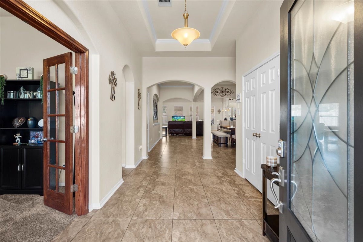 Entry hall with arched openings and French doors opening to a flexible room.