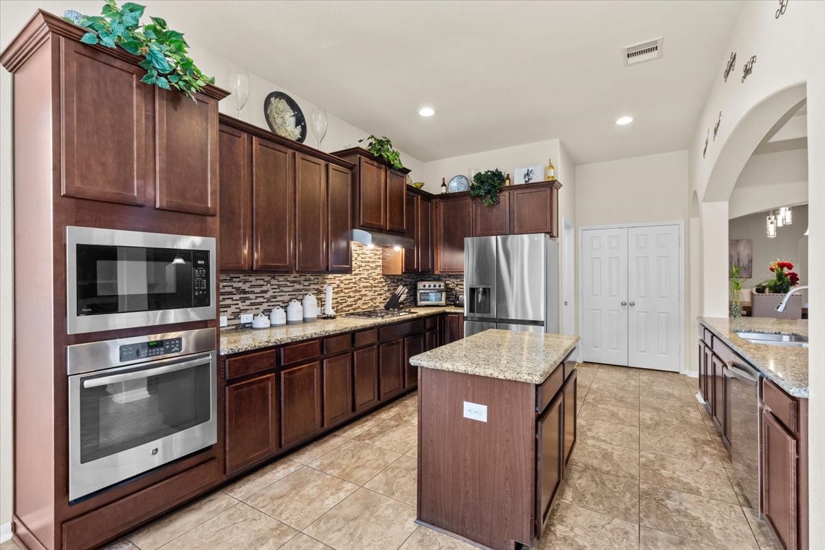 Kitchen with rich wood cabinetry, granite counters, stainless appliances, and a center island. Kitchen with rich wood cabinetry, granite counters, stainless appliances, and a center island.
