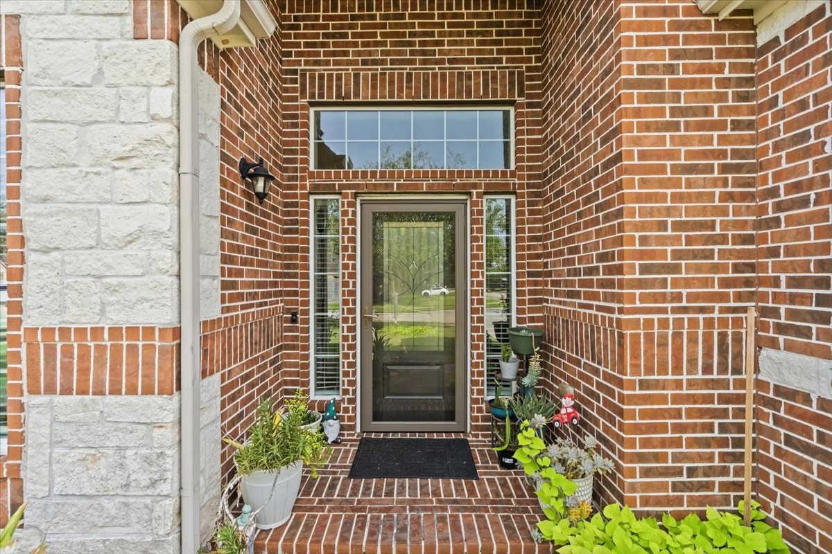 Charming covered front entry with brick and stone detail and a glass front door. Charming covered front entry with brick and stone detail and a glass front door.