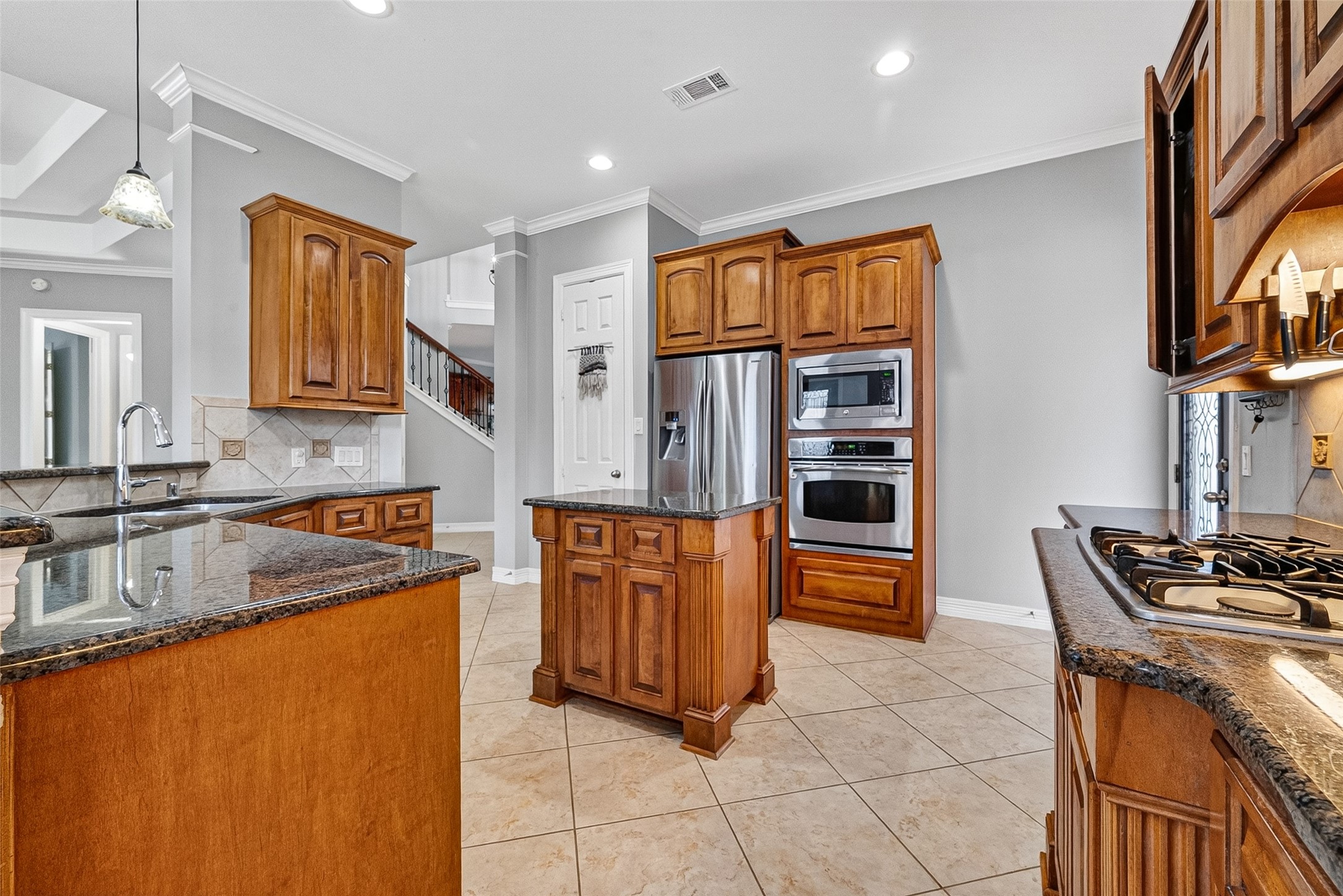 This inviting kitchen features modern appliances, warm wood cabinetry, and a spacious dining area with large windows providing plenty of natural light.