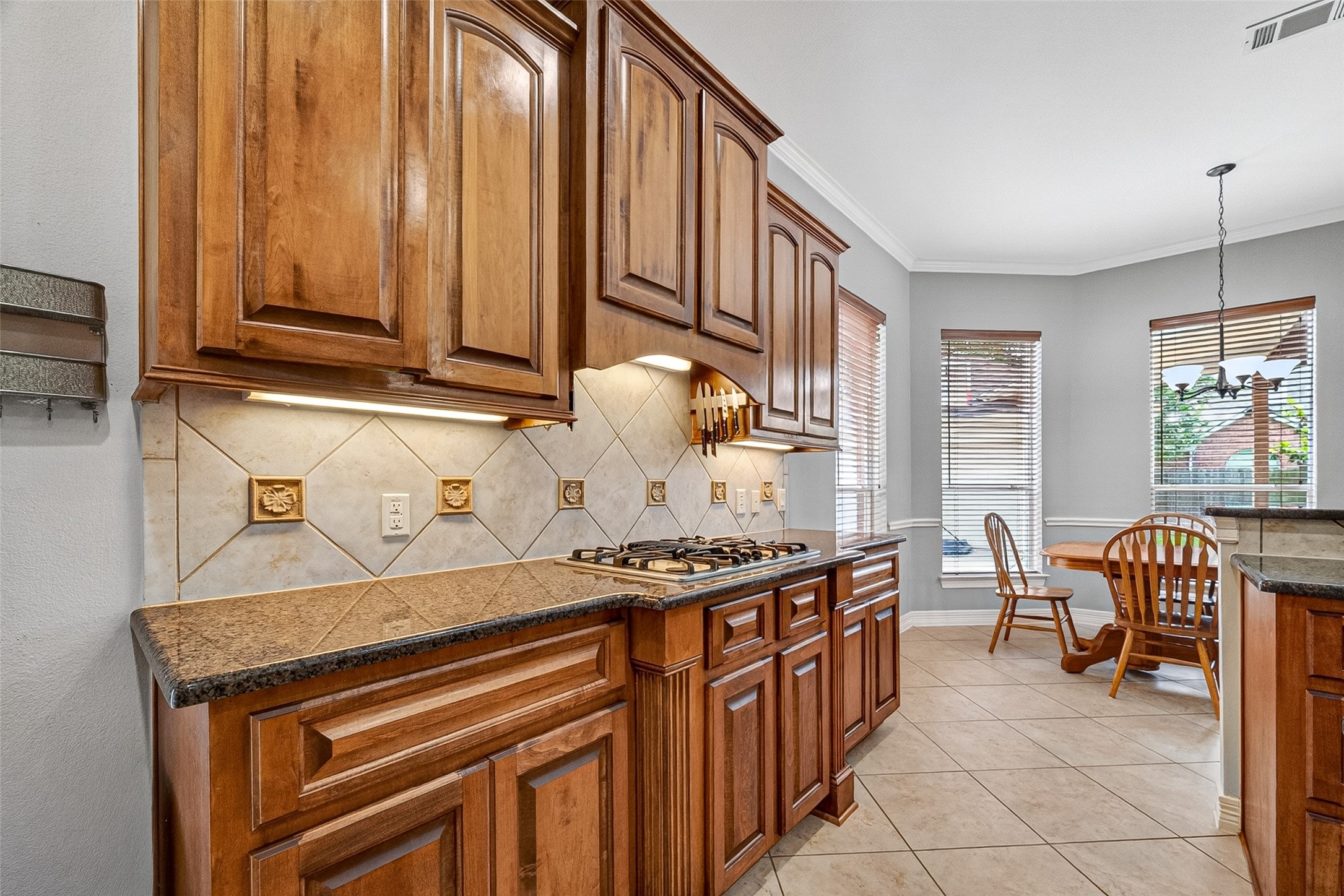 Spacious kitchen with elegant wooden cabinetry, granite countertops, and stainless steel appliances. Features a central island, gas cooktop, and ample natural light.