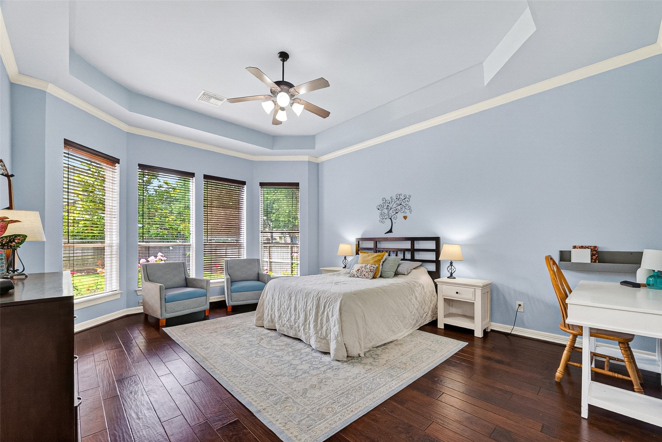 Downstairs primary suite with bay windows and tray ceiling.