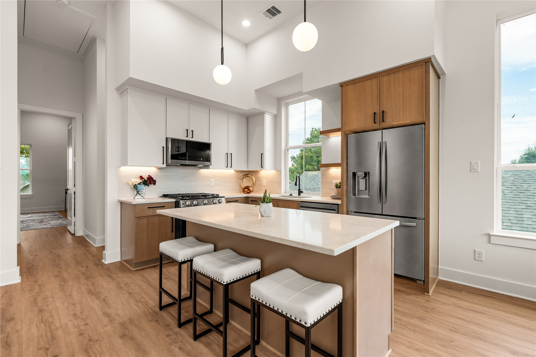 Gourmet kitchen complete with two-tone cabinetry, quartz counters, stainless gas appliances, and a center island.