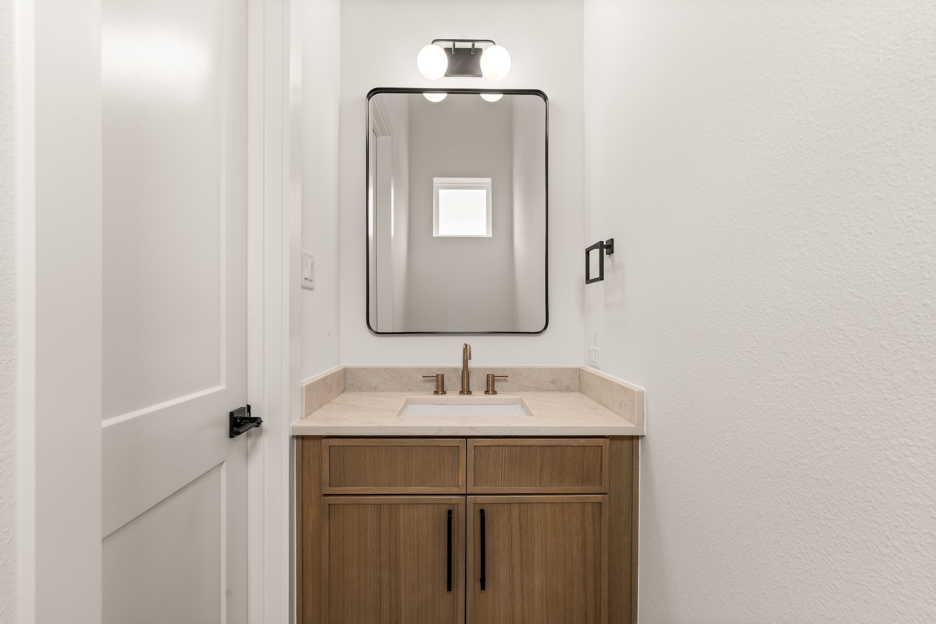 Convenient powder room with natural-toned vanity and warm brass fixtures serving guests on the living floor.