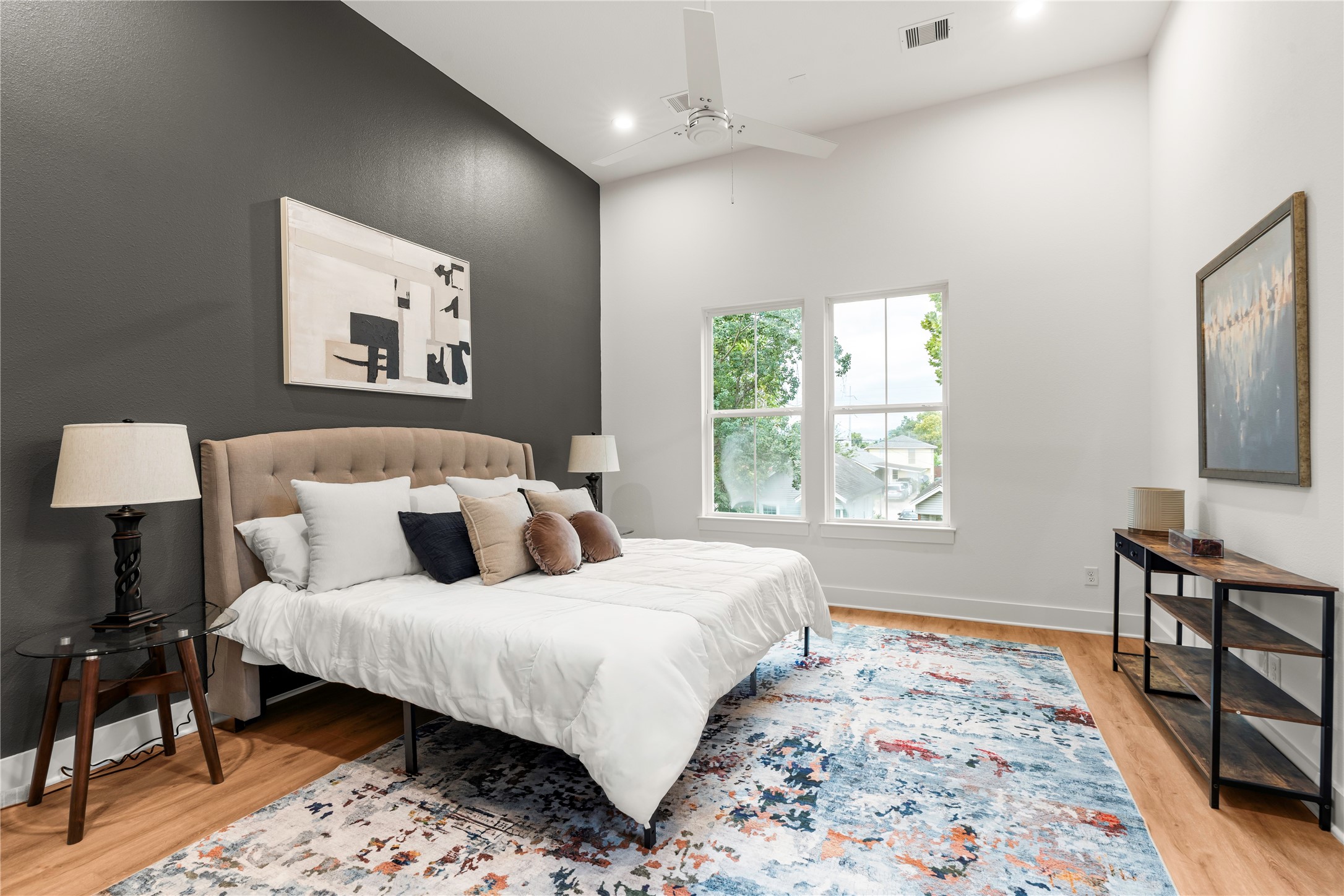 Peaceful primary bedroom retreat featuring high ceilings and dark accent design wall.