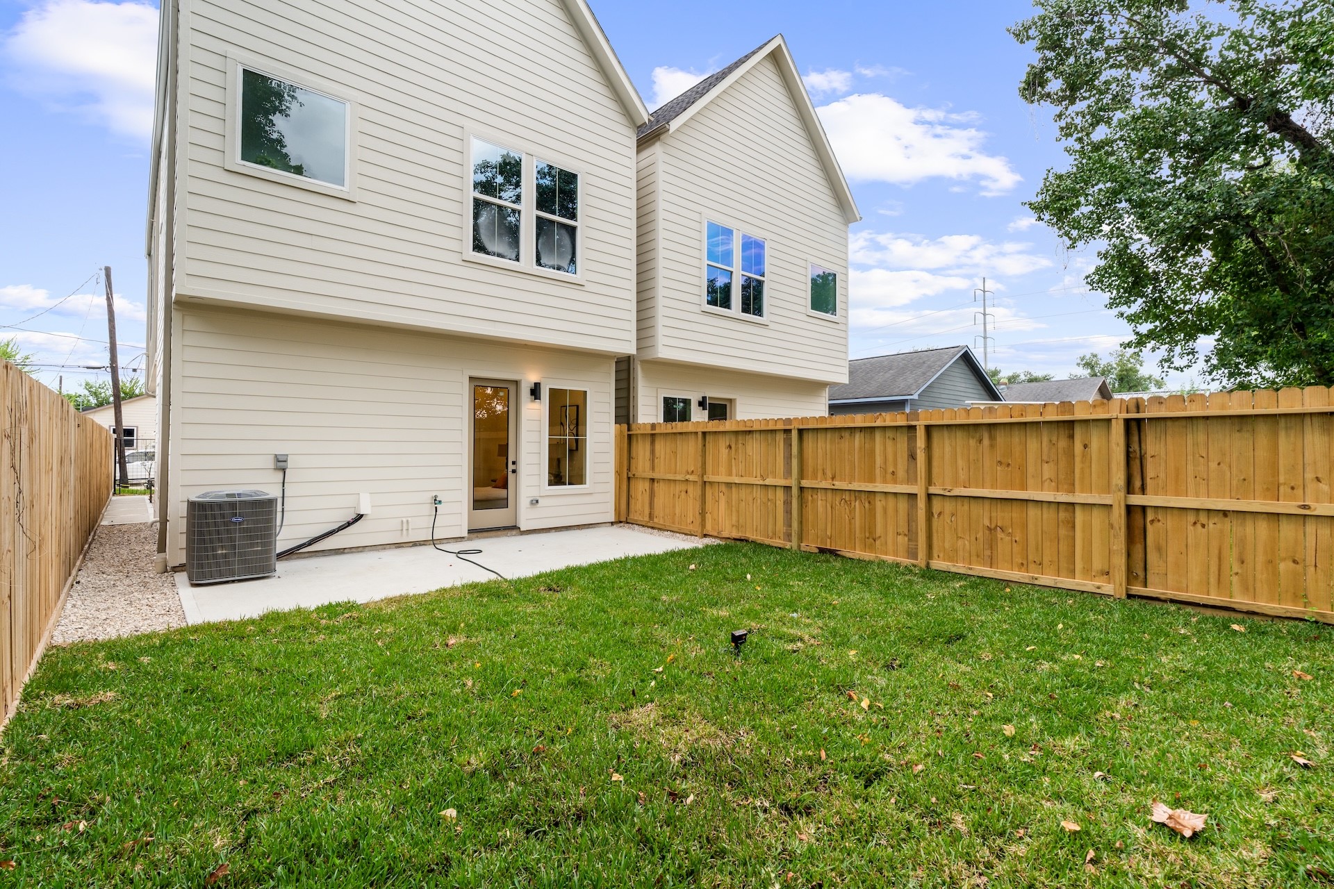 Private, fully fenced backyard featuring a grassy lawn and covered concrete patio space.