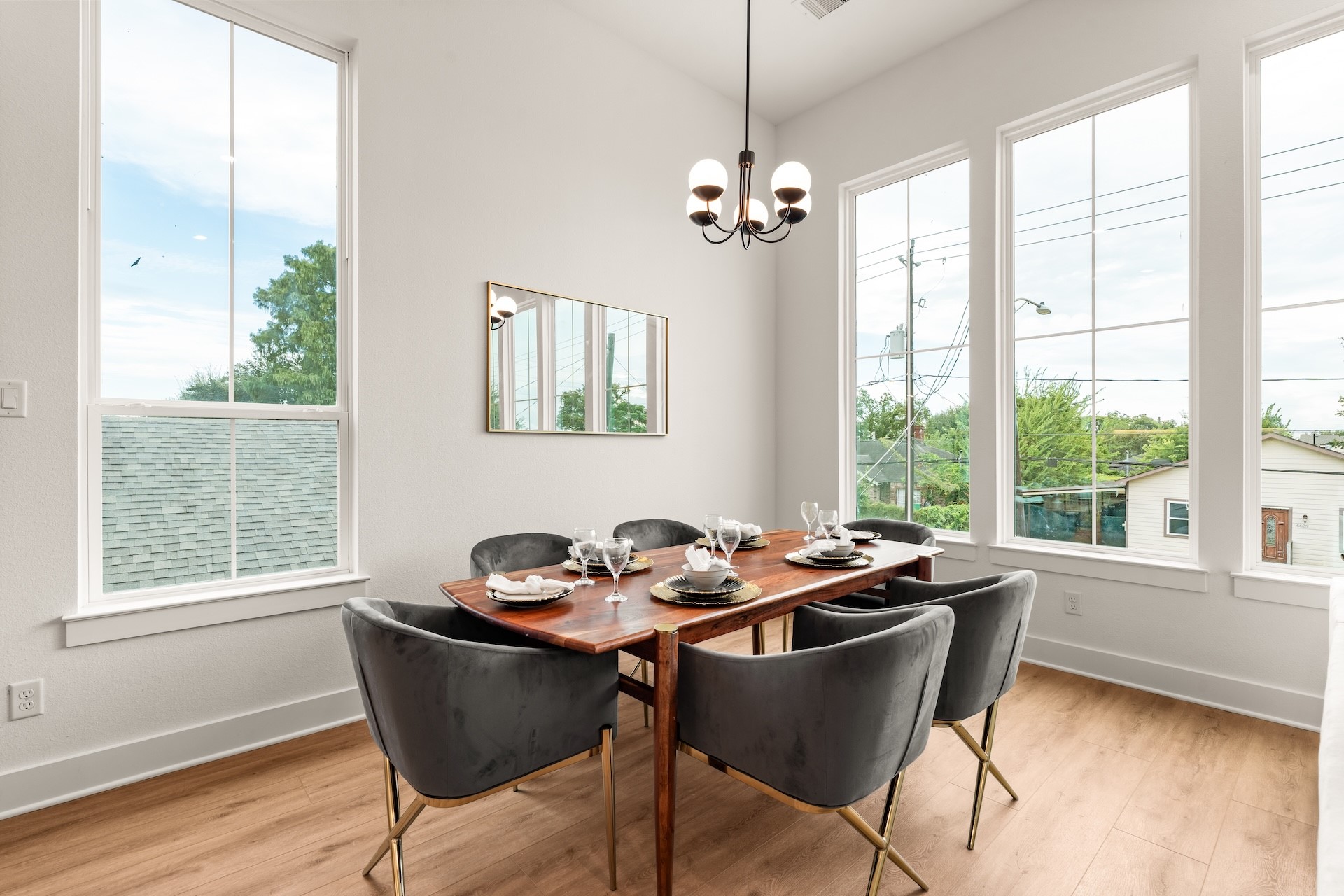 Elegant dining room layout highlighted by designer lighting and sweeping tree-lined neighborhood views.