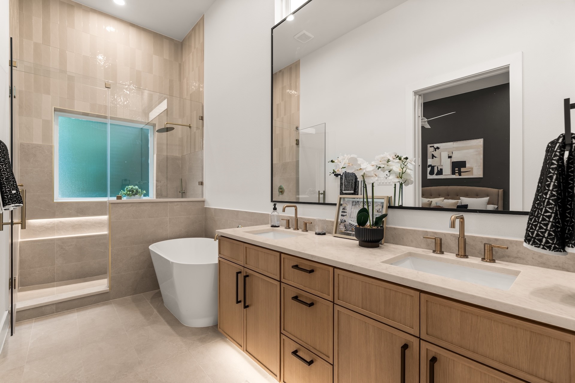Luxurious primary bathroom featuring a freestanding soaking tub, dual vanities, and a frameless glass shower.