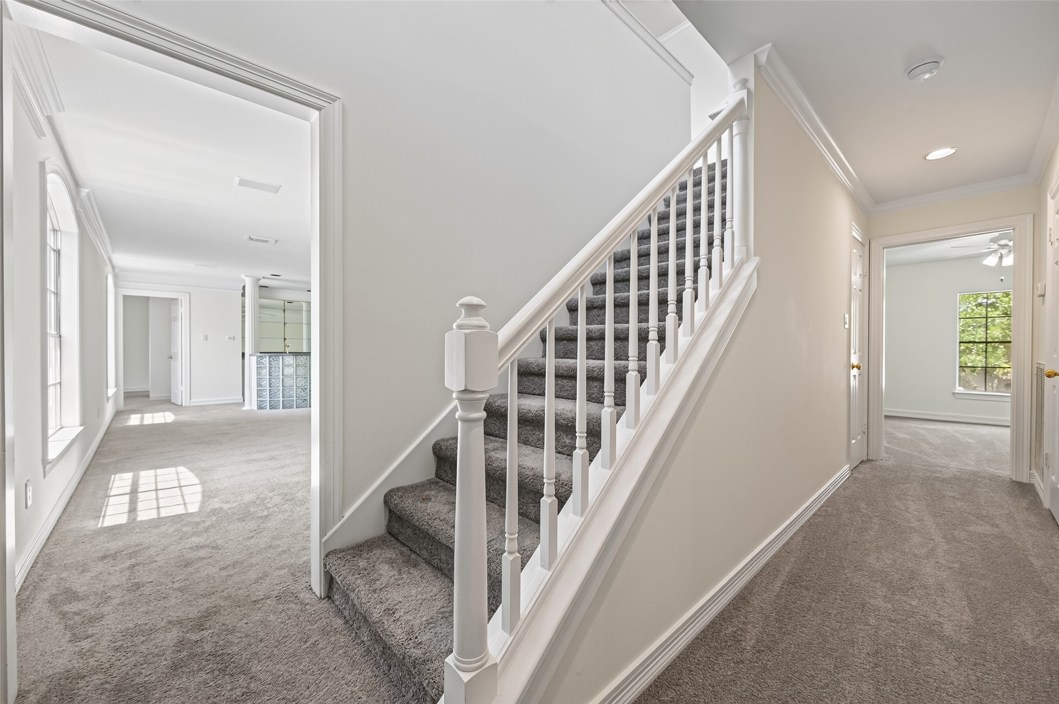 Spacious hallway with plush carpeting leads to a bright living area and features a stylish staircase, the third level.