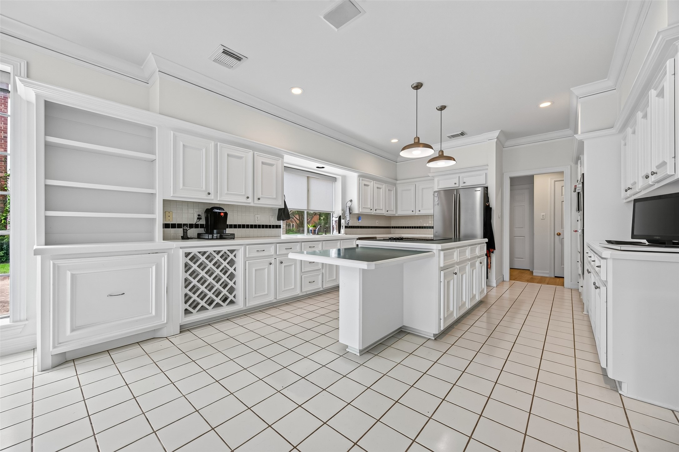 Bright and spacious kitchen featuring bright cabinetry, a large central island with pendant lighting, and ample counter space. Perfect for culinary enthusiasts.