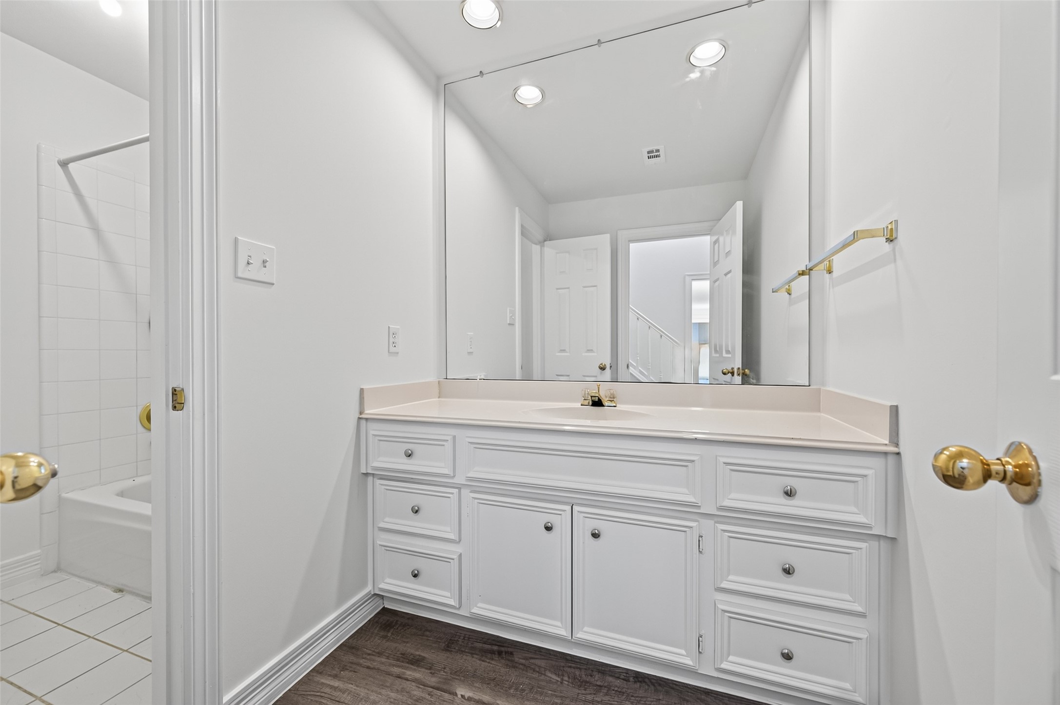 Bright and spacious bathroom featuring a large vanity, and a wide mirror.
