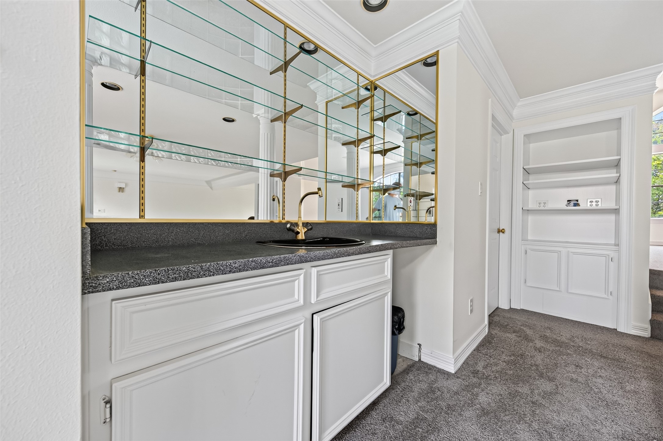 Elegant wet bar area featuring sleek countertops, glass shelving, and ample cabinetry, perfect for entertaining or additional storage.