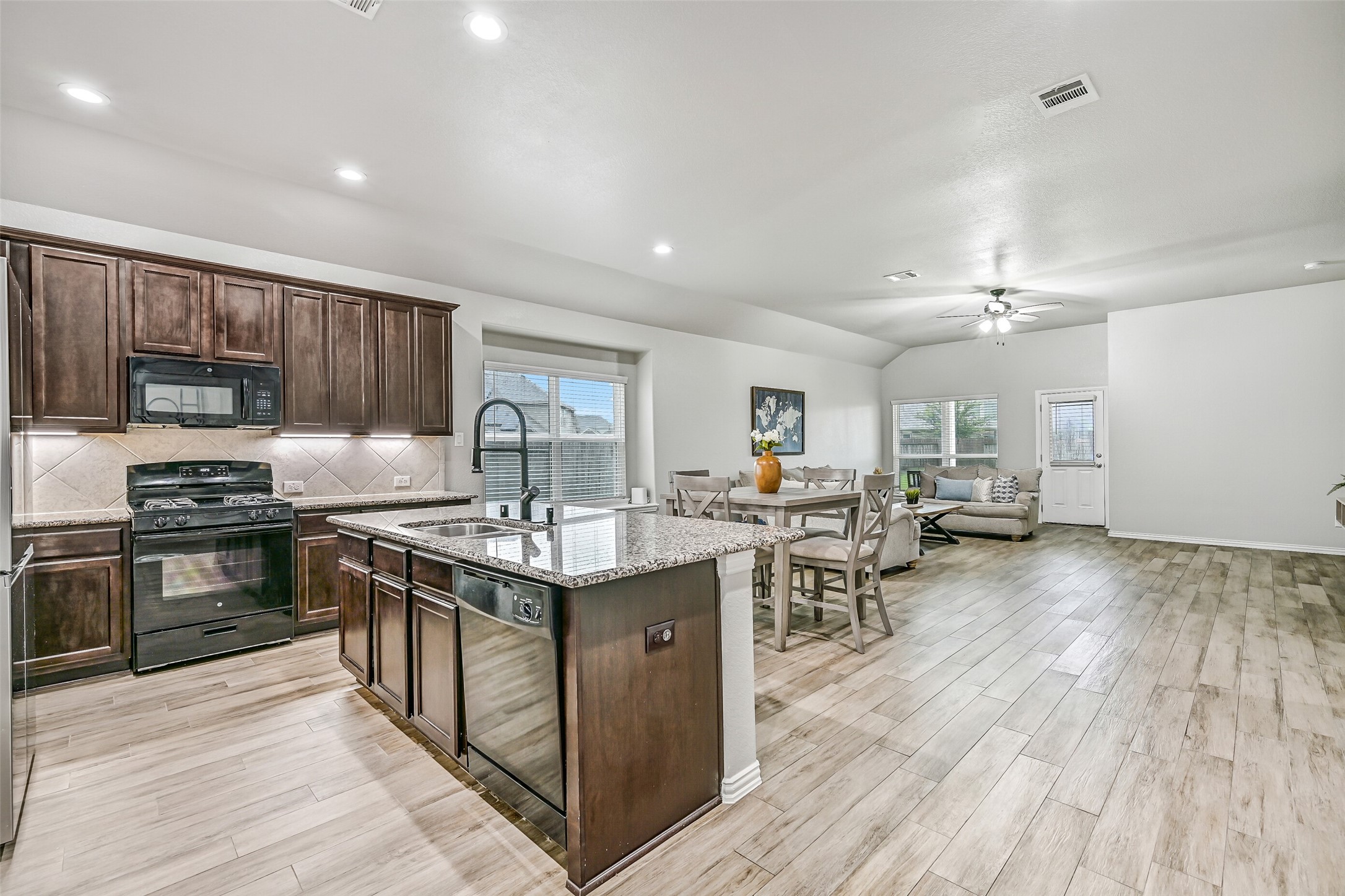 Dark espresso cabinetry provides a beautiful contrast against the neutral finishes, while the gas cooking, granite counters, and generous workspace make this kitchen equally suited for weeknight meals or entertaining family and friends.