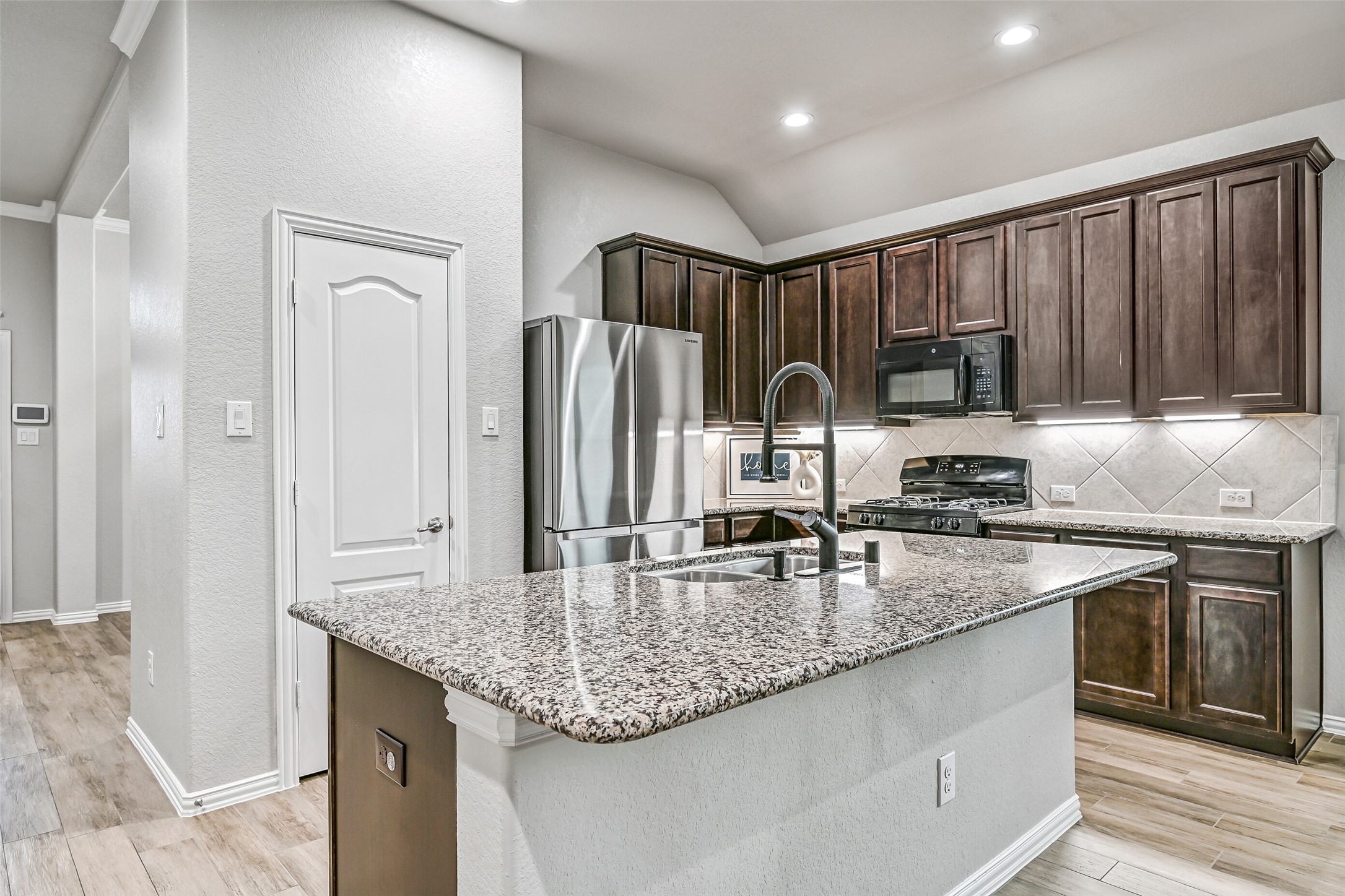 The island kitchen is beautifully appointed with granite countertops, rich 42-inch espresso cabinetry, under-cabinet lighting, stainless appliances, a spacious pantry, and a breakfast bar that's perfect for casual meals or visiting with guests.