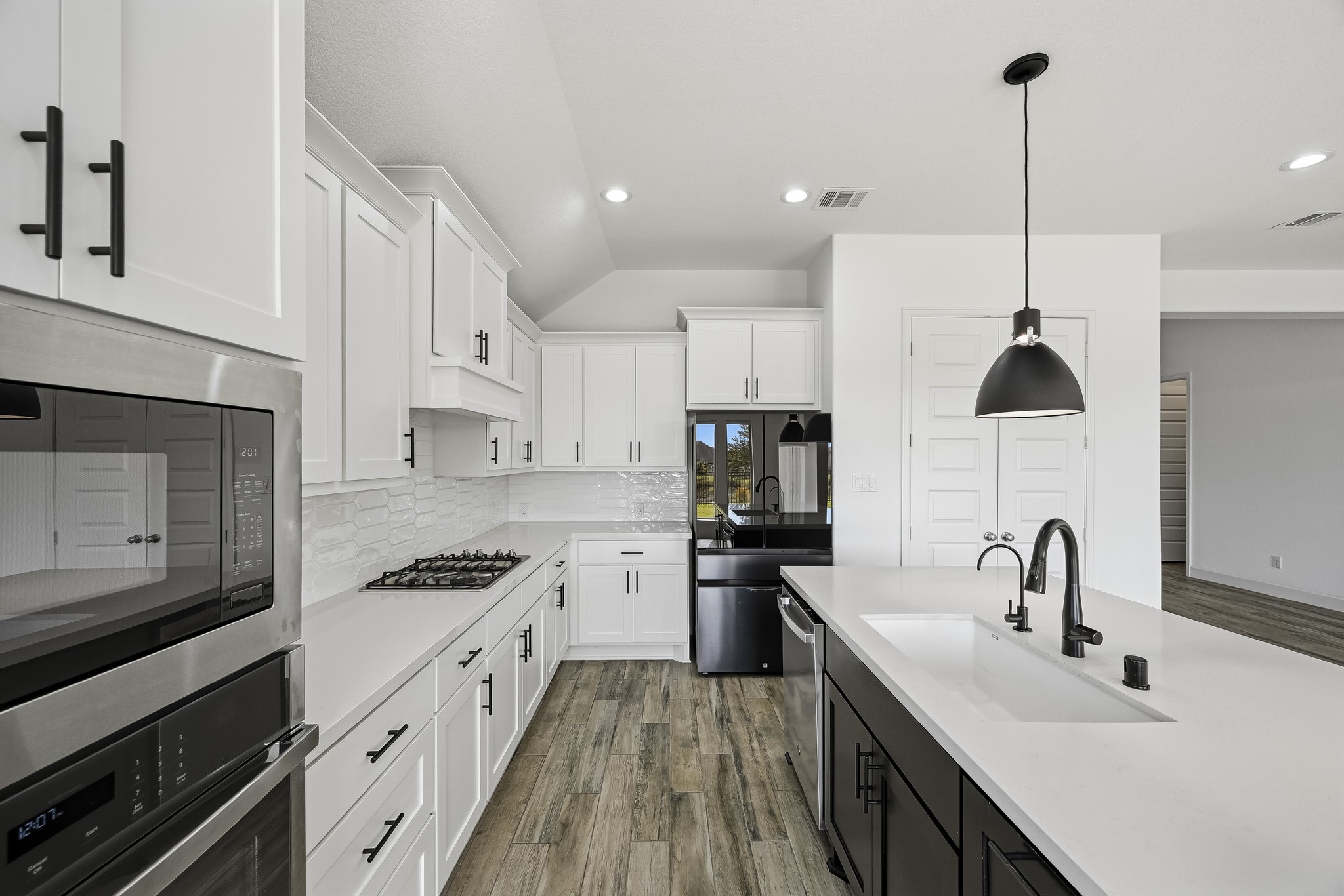 This functional workspace maximizes prep surface and storage capacity. Integrated task lighting and enduring wide-plank floors create a seamless, fluid transition into the adjacent living quarters.