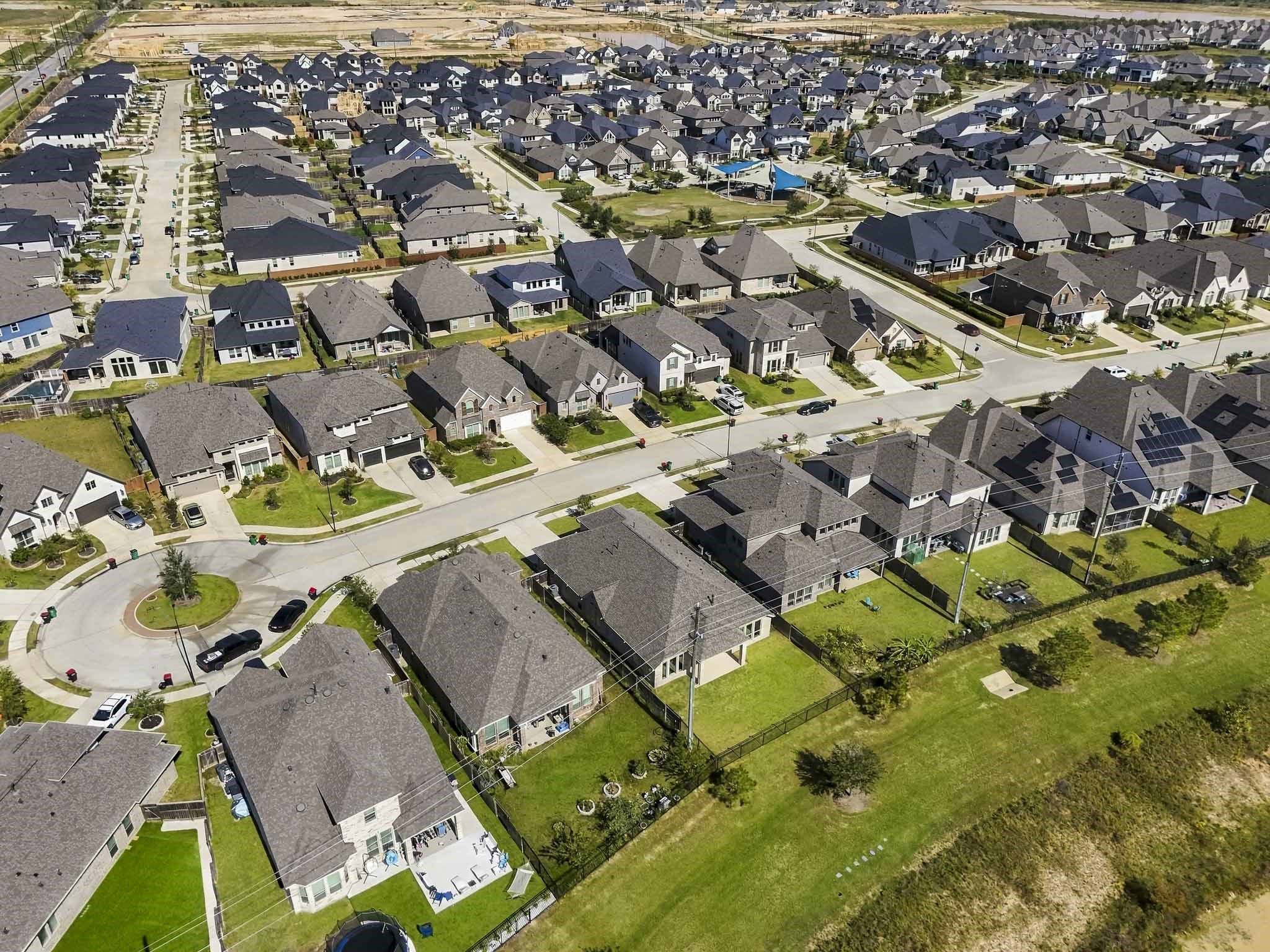 This aerial overview highlights the master-planned neighborhood's open setting and organized streetscapes. The property enjoys generous spacing, an adjacent greenbelt, and a peaceful suburban environment.
