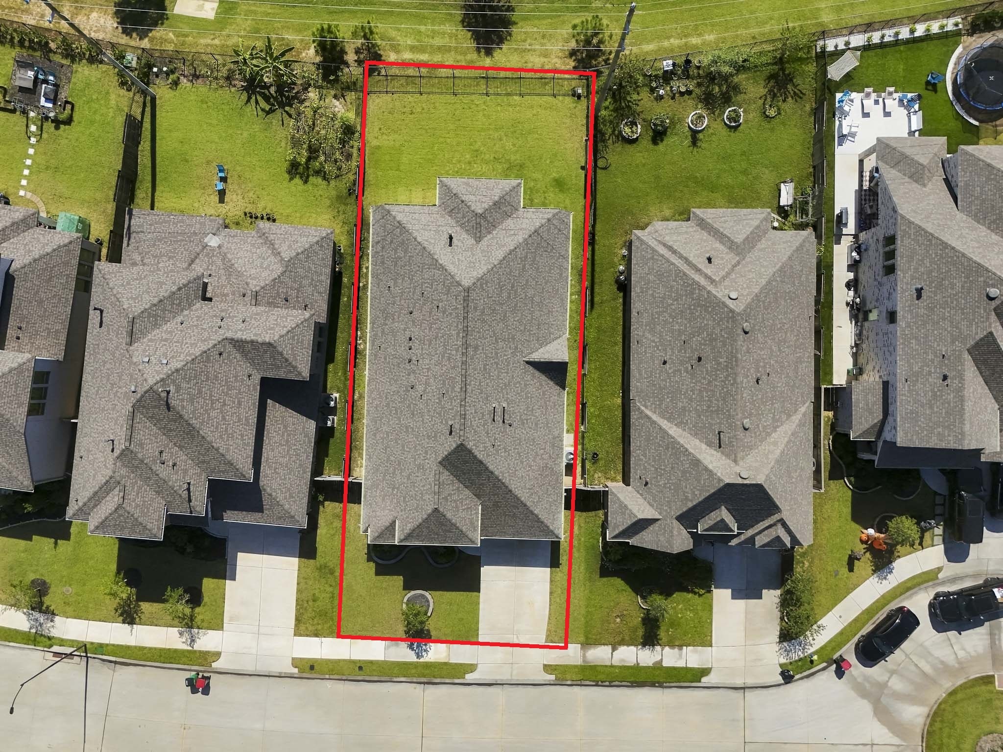 An aerial perspective of the property reveals its spacious and level layout within a planned residential neighborhood. Features include a sizeable, fenced-in backyard, a deep covered back patio, and a driveway at the front.