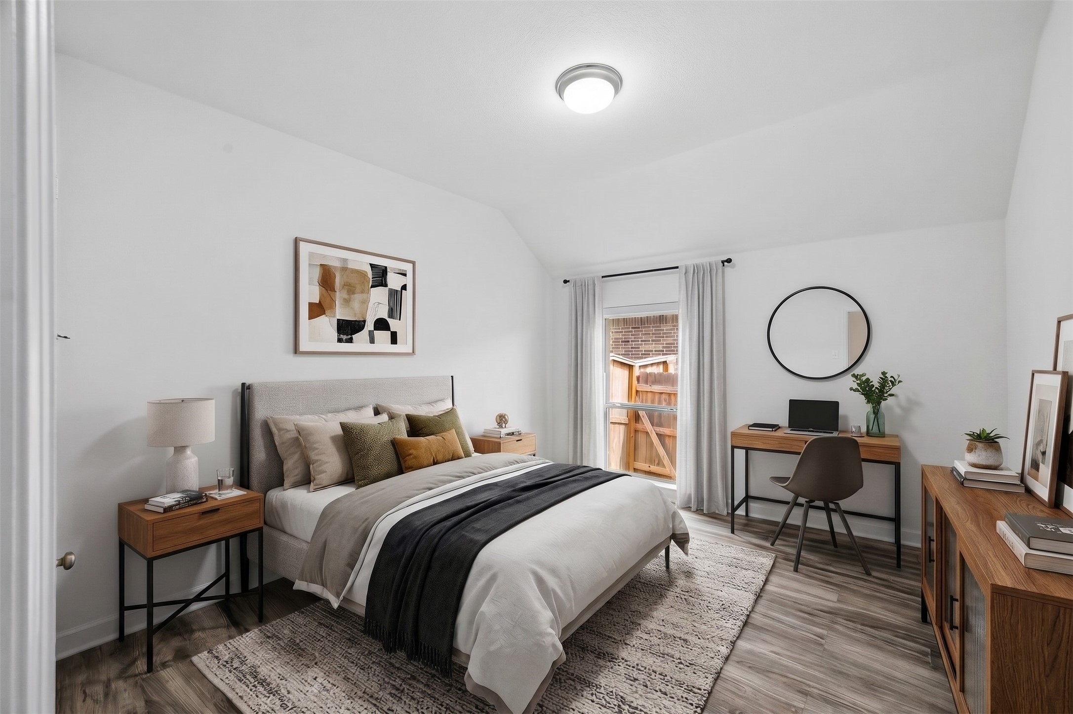 Virtually Staged: This bright contemporary bedroom features soaring vaulted ceilings and low-maintenance wood-style flooring. The open layout effortlessly accommodates a complete bed set, accent storage.