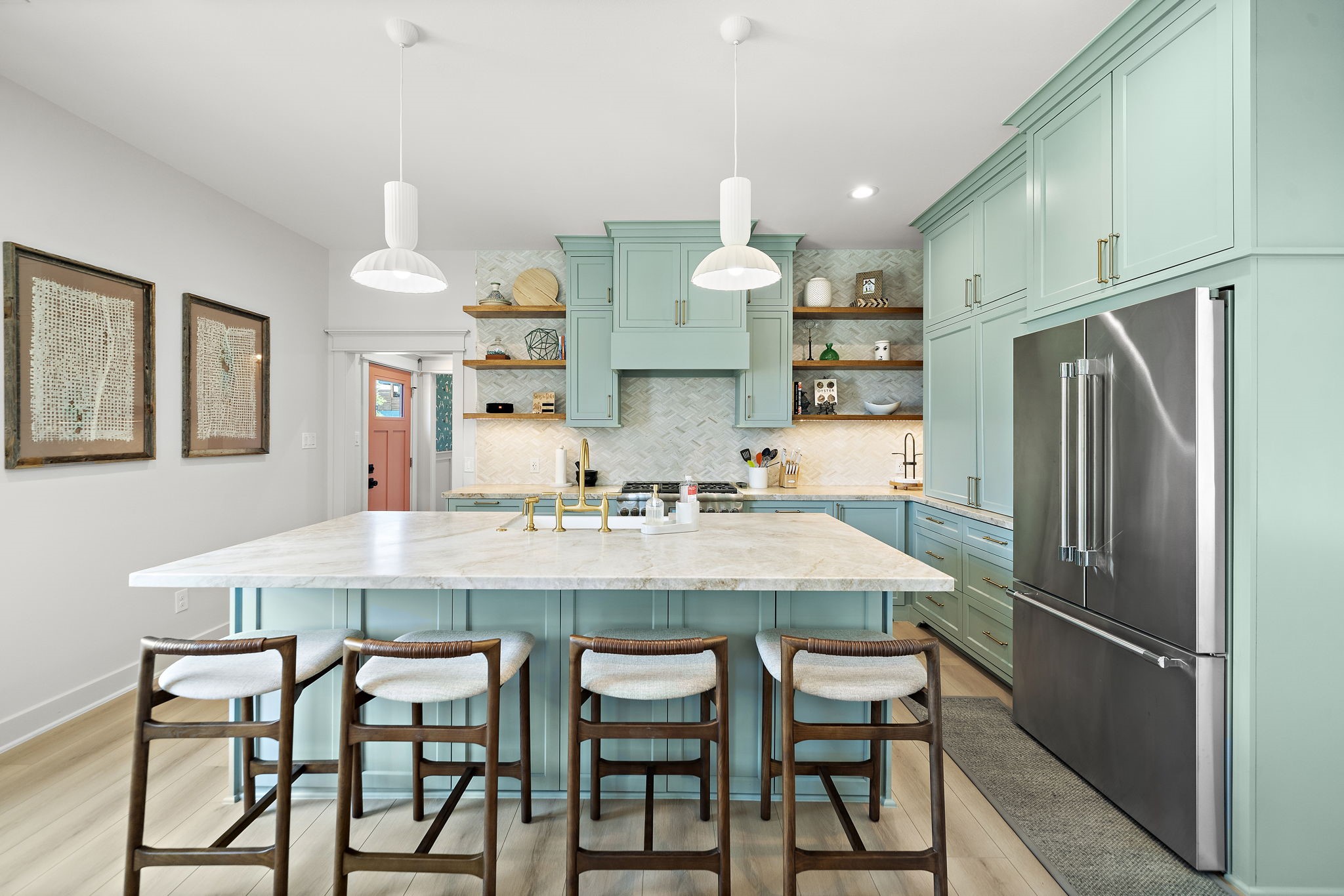View of the kitchen island with bar seating, hallway to bedrooms on the left, fridge and coffee bar on the right.
