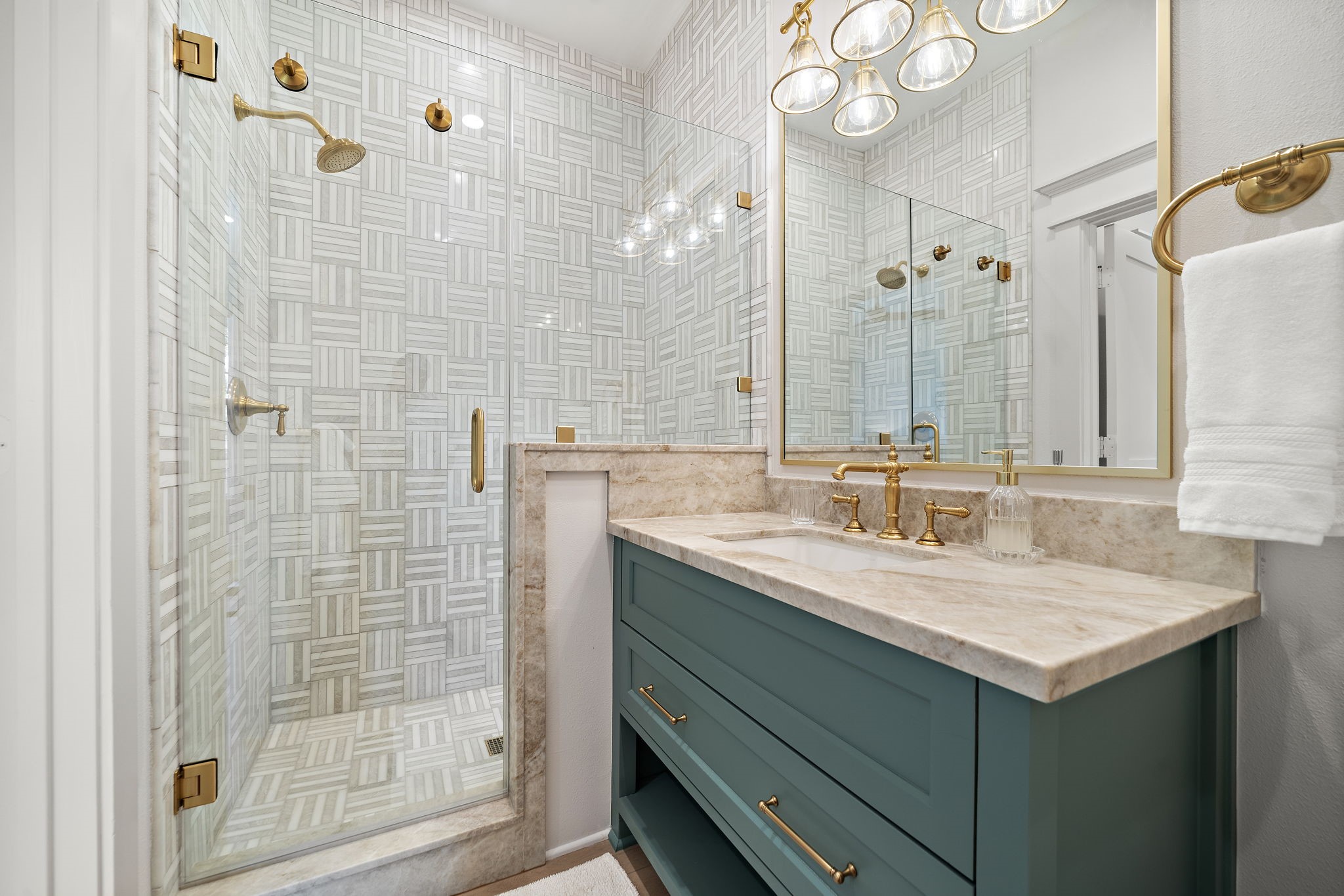 Bathroom with gorgeous finishes including walk-in shower, quartzite countertops, and brass Kohler fixtures.