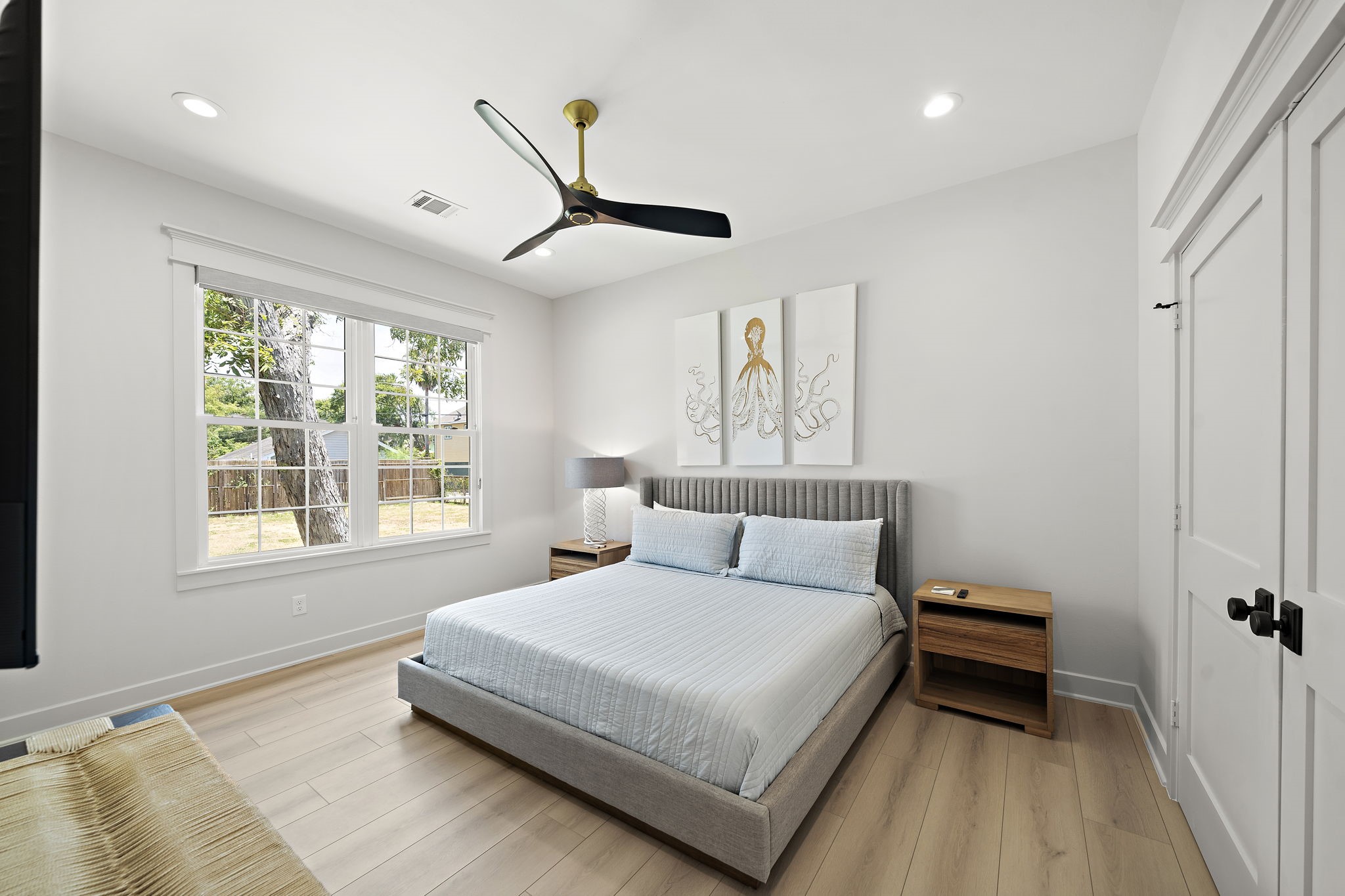 View of the spacious primary bedroom at the back of the home. Includes black out custom blinds and built-ins within closet.
