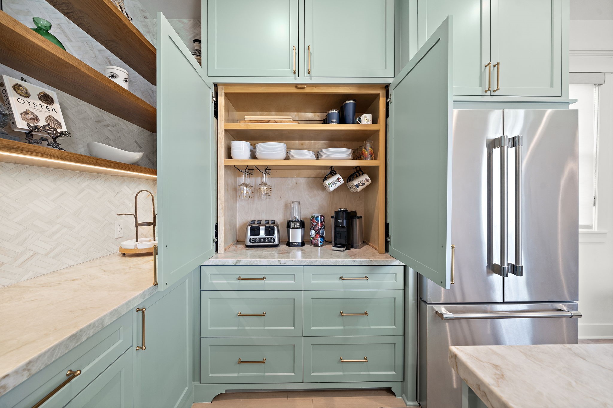 A dedicated built-in coffee bar in the kitchen, with drawers that provides for storage and stainless steel fridge.