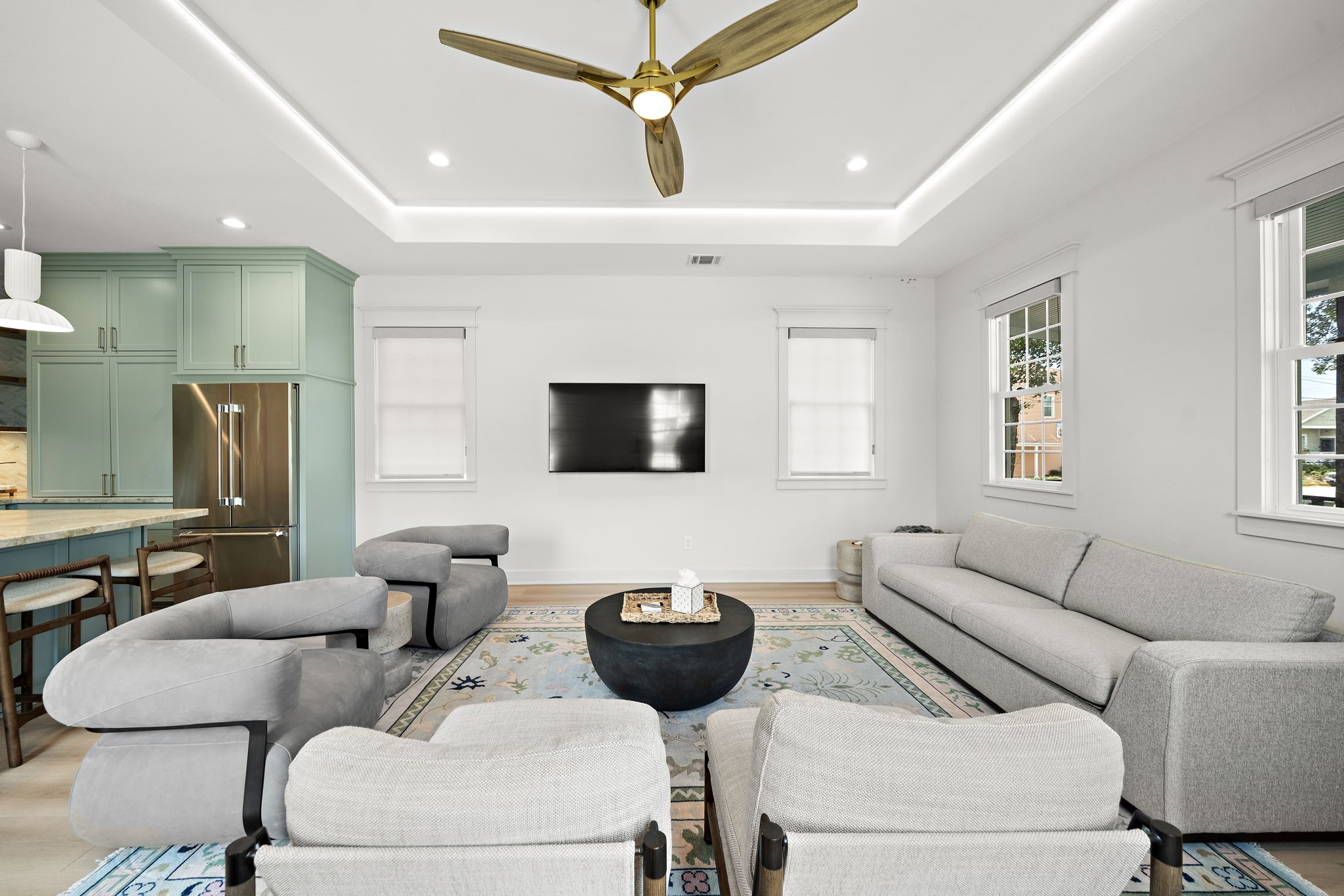 Spacious living room with recessed ceiling with rope lighting, Miele fan, and tons of natural lighting.