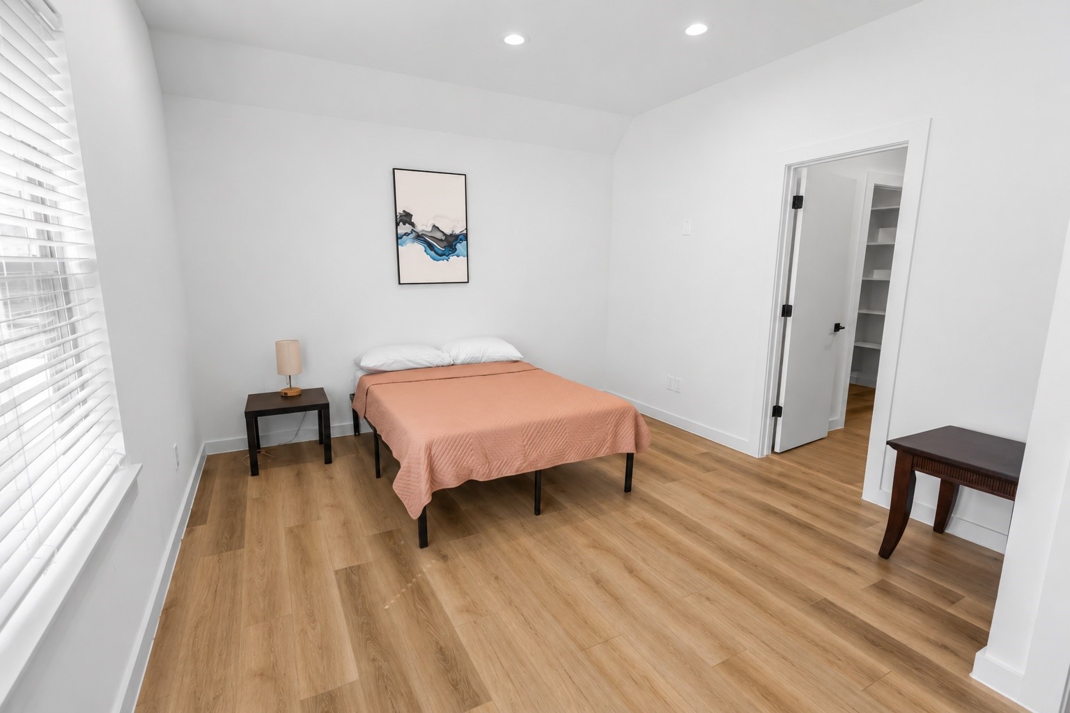 Comfortable secondary bedroom on the third floor offers generous proportions with soaring ceilings, warm wood look flooring, and enough space for a bedroom suite plus a media or seating area. Double closets provide excellent storage while the private en suite bath creates an ideal setup for guests, roommates, or multigenerational living.