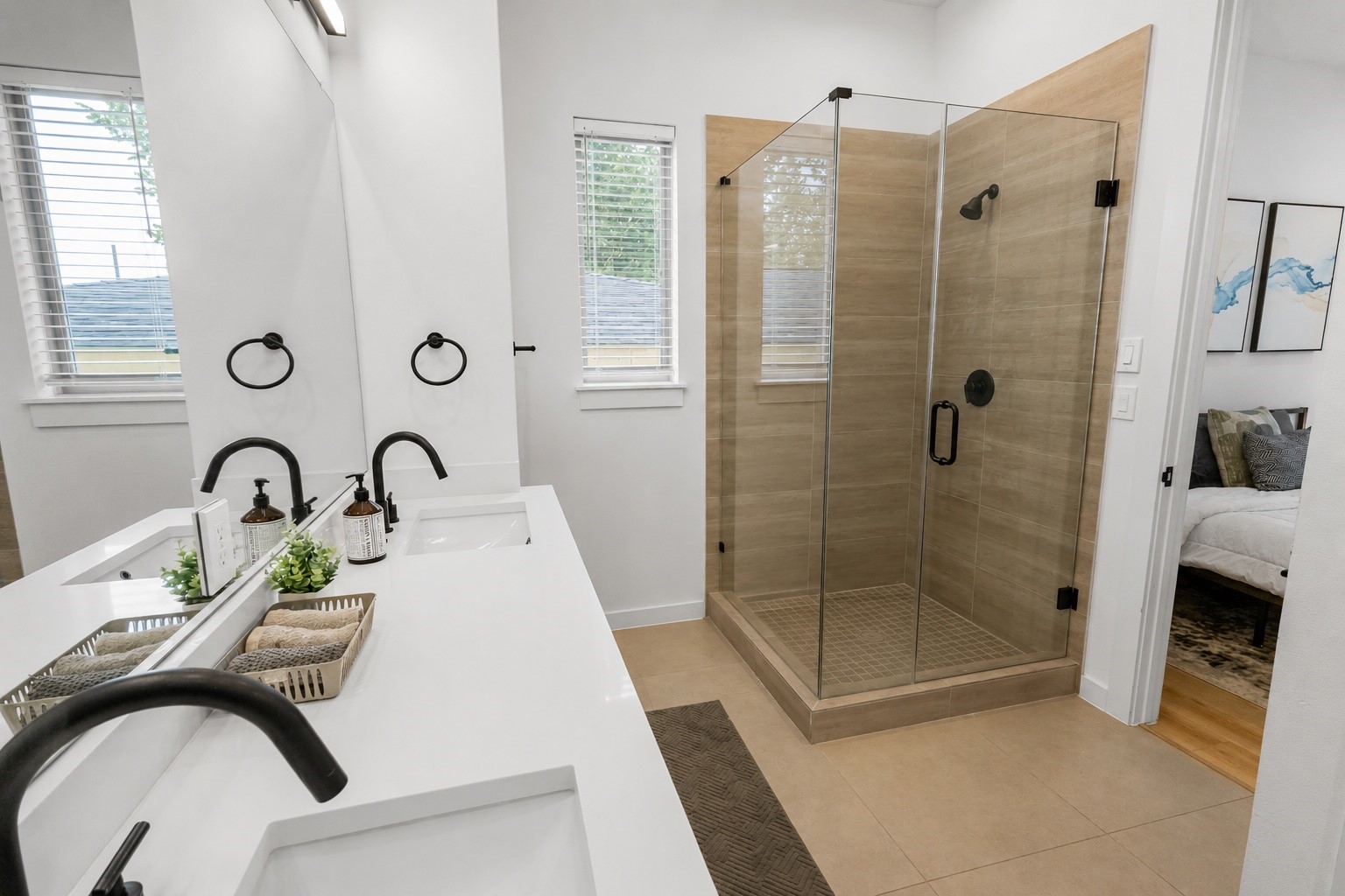 Modern finishes elevate this spa inspired primary bath with a frameless glass shower, oversized vanity, quartz countertops, matte black fixtures, and warm porcelain tile. Clean lines and timeless materials create a polished space that blends style with everyday functionality.