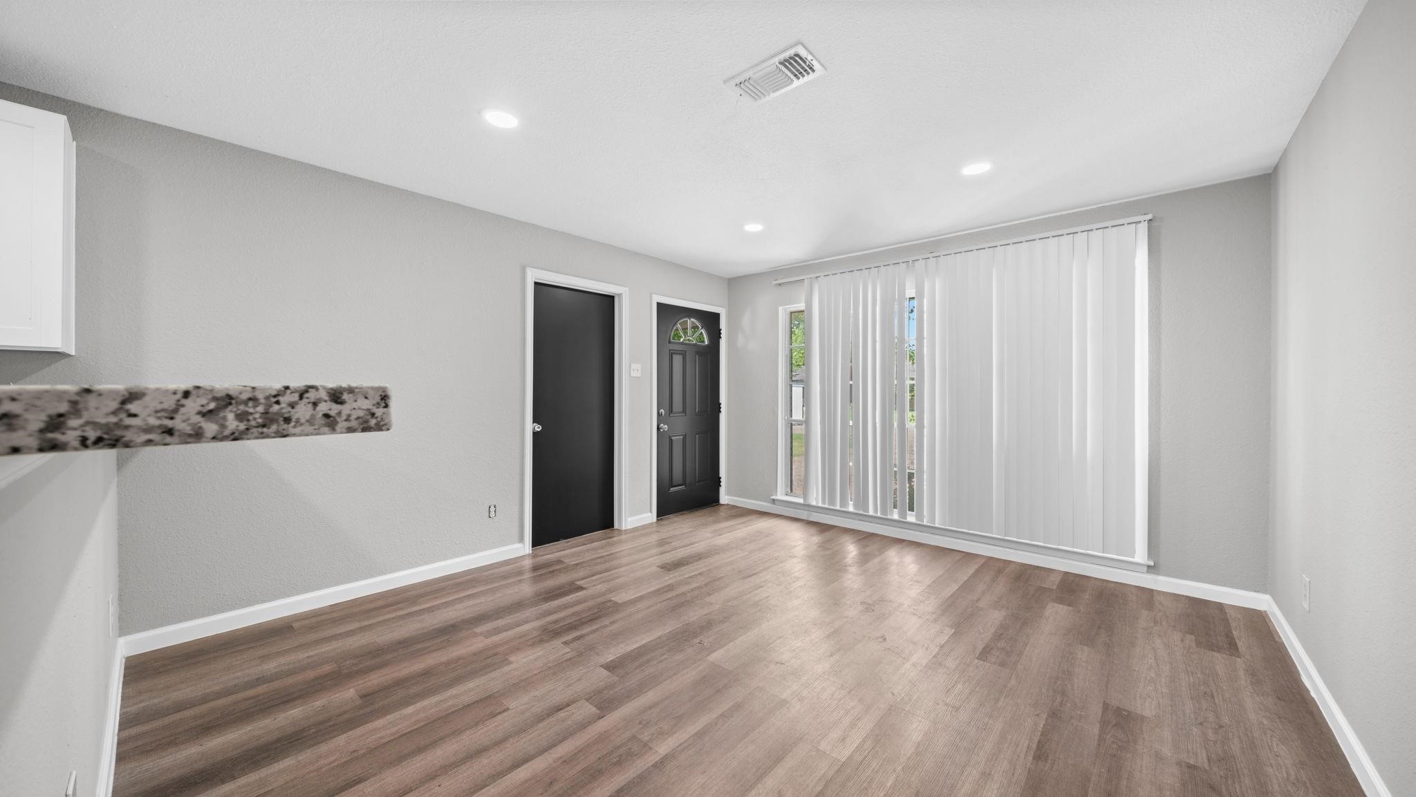 Recessed lighting casts a warm, inviting glow throughout the open-concept living space, highlighting its seamless flow between the kitchen and living areas while creating an elegant atmosphere for both relaxed living and sophisticated entertaining.