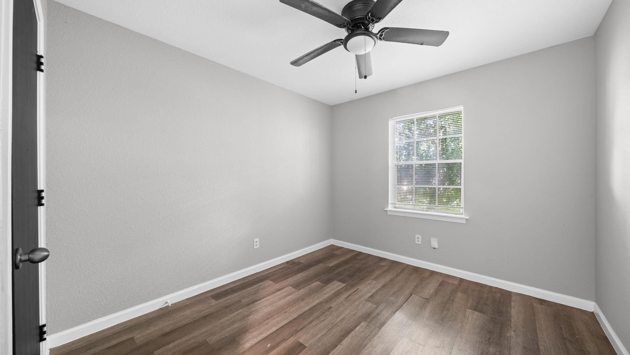 The fourth bedroom offers an appealing combination of comfort and versatility, featuring luxury vinyl flooring, a window with blinds, a ceiling fan with integrated lighting, and a spacious walk-in closet. This well-appointed space easily accommodates guests, a private home office, or a creative studio.