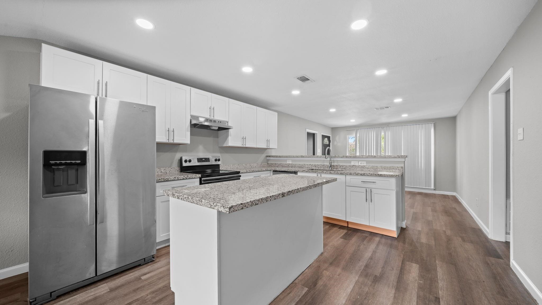 The kitchen features a suite of stainless steel appliances, including a GE electric range and oven, dishwasher and a deep stainless steel sink designed to accommodate larger cookware. A Whirlpool refrigerator, included with the home, completes this beautifully appointed and functional space.