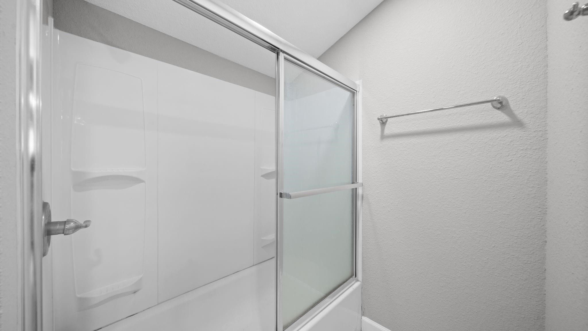 The elegantly appointed bath features a tub and shower combination with sliding glass doors completes this beautifully designed space.