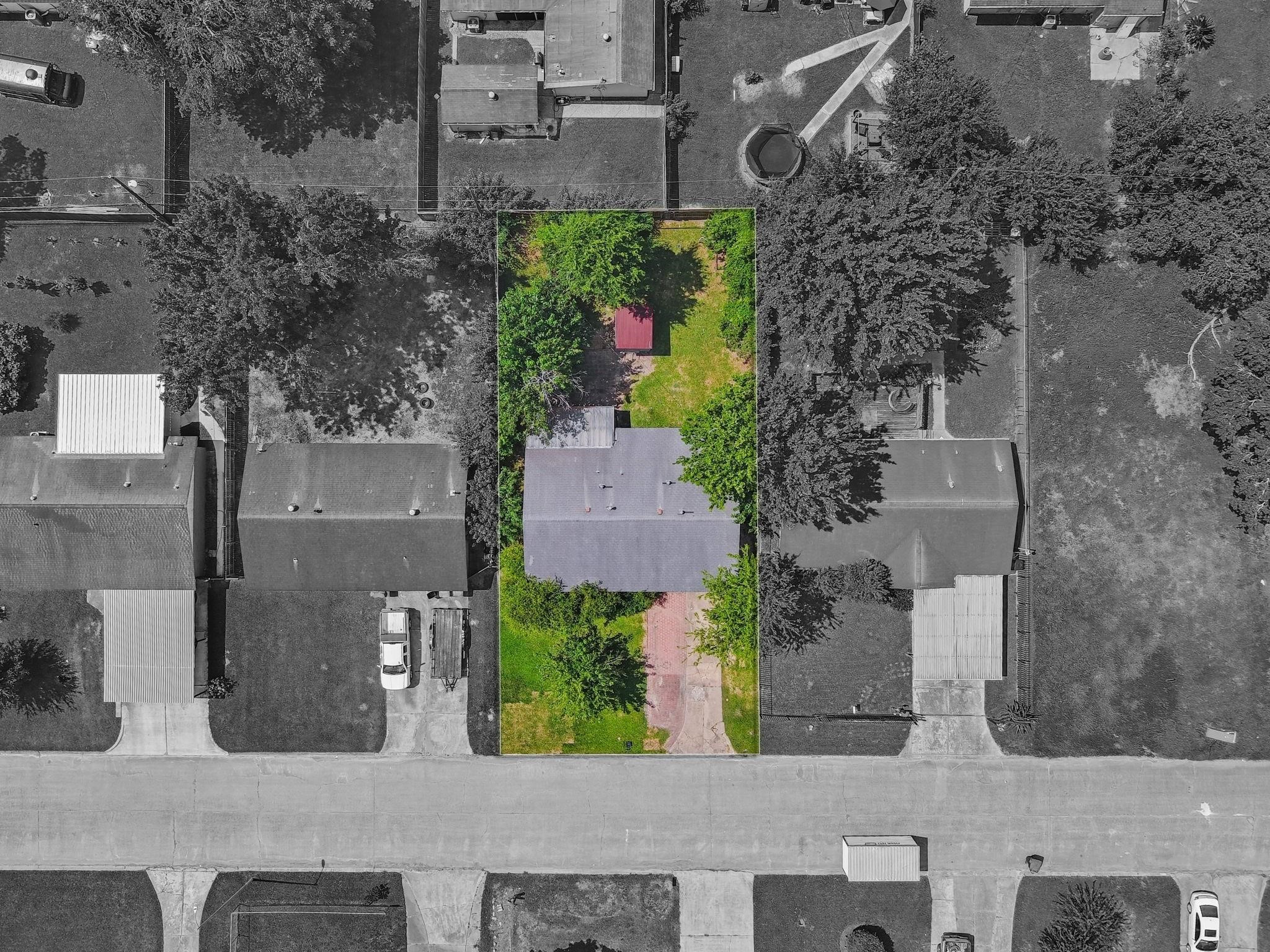 An aerial perspective showcases the exceptional space and possibilities of the expanded backyard. Framed by mature trees, this inviting outdoor setting features a covered patio, expansive lawn, and ample room for lush gardens, recreation, or a beautifully designed outdoor oasis.