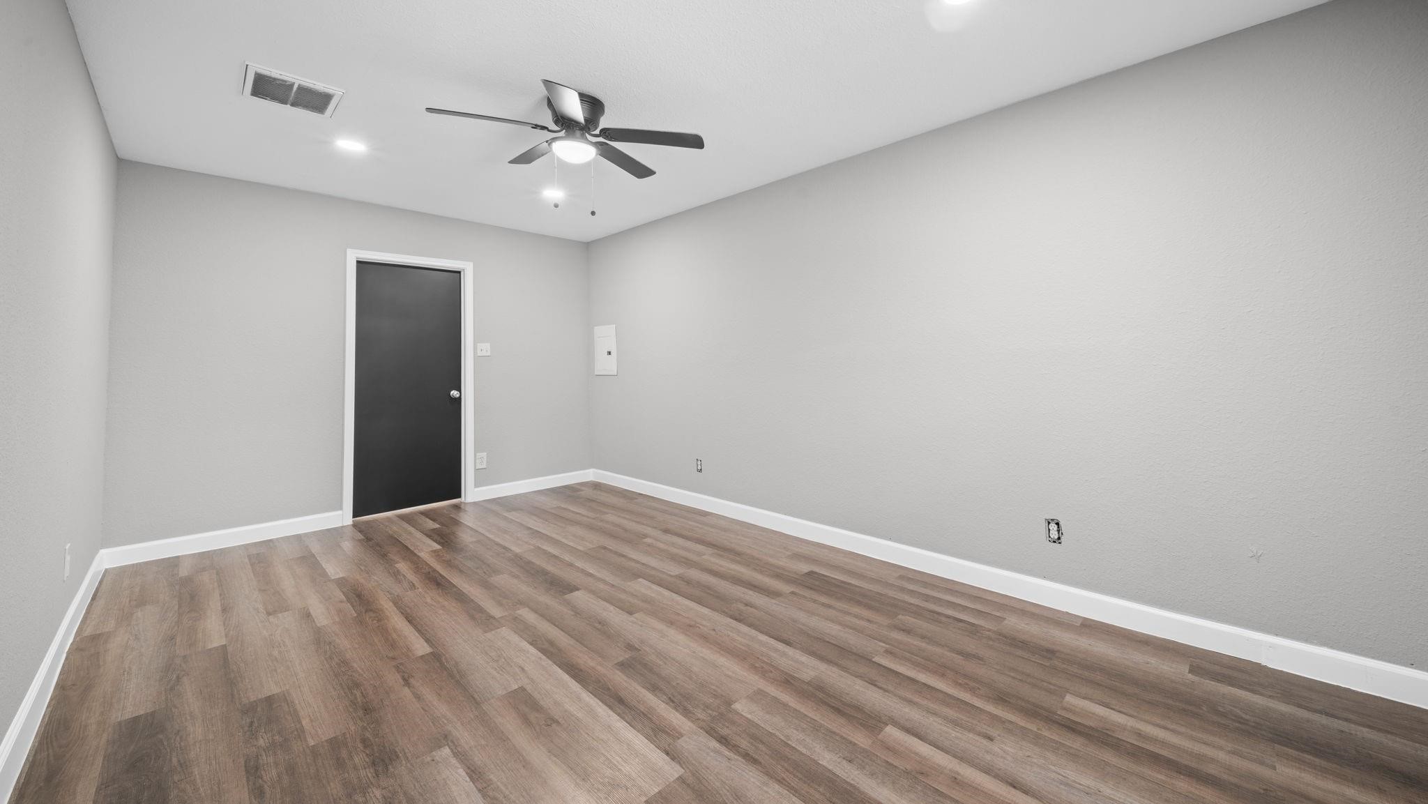 Originally converted from the garage, the expansive primary suite offers an exceptional sense of space and comfort. Luxury vinyl flooring, recessed lighting, and a ceiling fan with integrated lighting complement the rooms welcoming ambiance, creating a relaxing private retreat with ample space for a beautifully appointed bedroom setting.