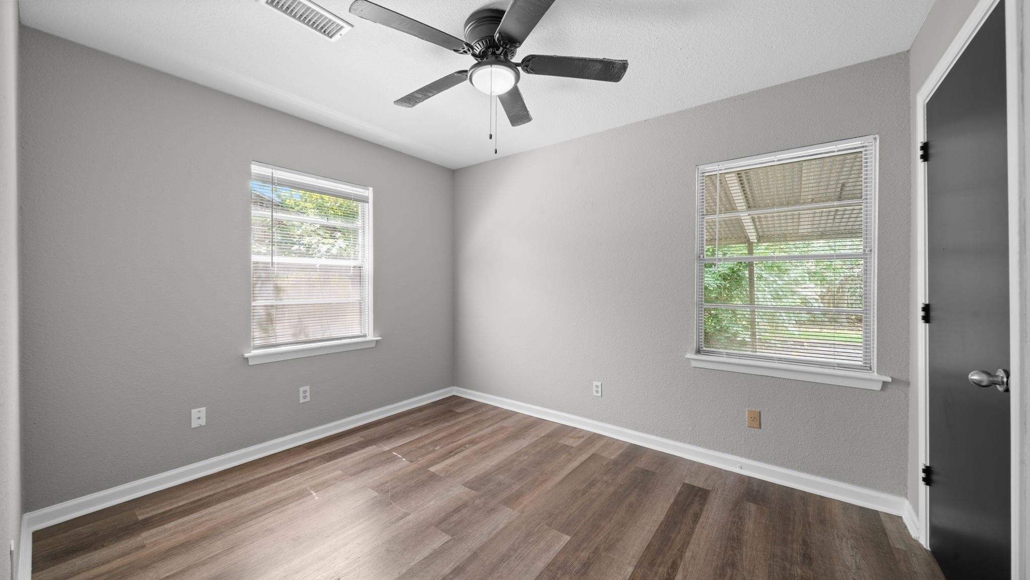 The third bedroom offers a bright, welcoming atmosphere, with two windows featuring blinds that invite natural light into the space. A ceiling fan with integrated lighting adds comfort, while a spacious walk-in closet provides ample storage and organization.