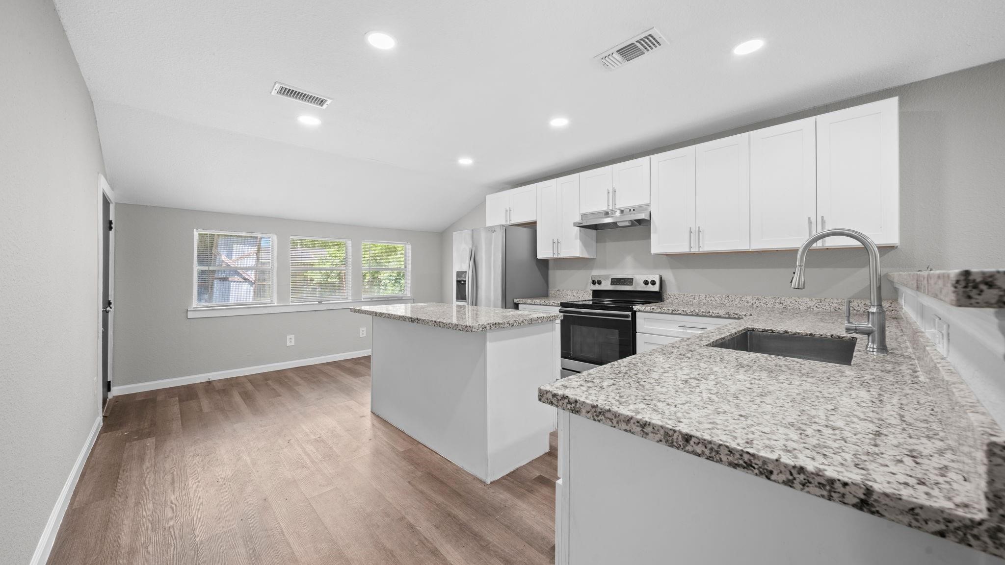 Elegant granite countertops complement an expansive 10-foot breakfast bar, offering generous workspace for culinary preparation, casual dining, and a welcoming place to gather.
