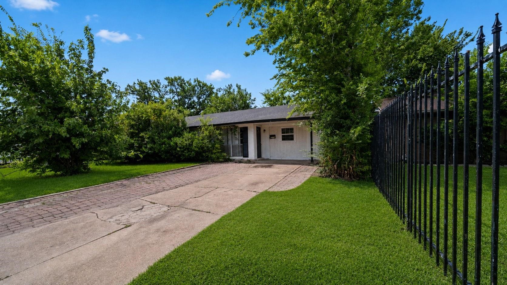 Mature shade trees and a spacious paved driveway create inviting curb appeal with plenty of room for guests.