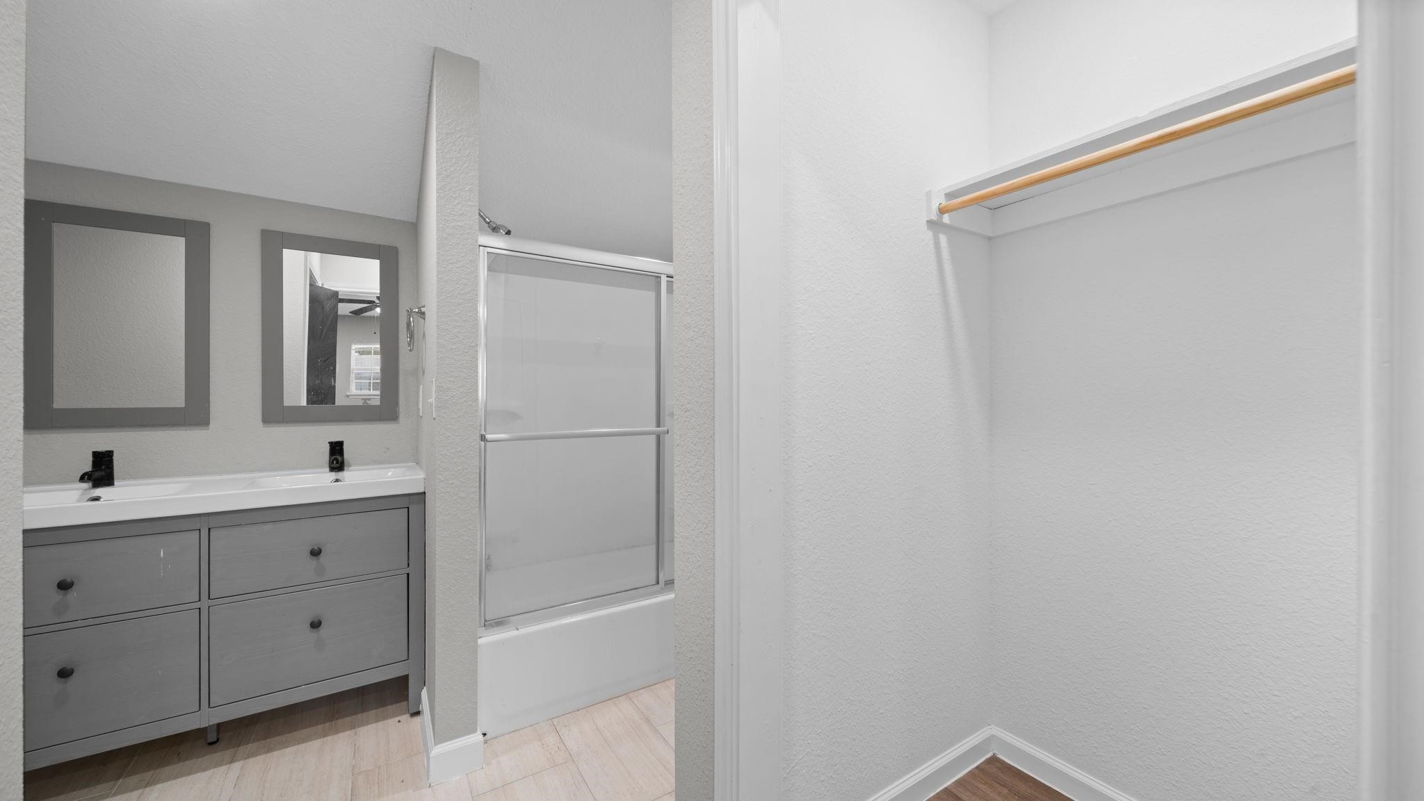 The en-suite primary bath showcases an expansive dual-sink vanity complemented by sleek contemporary cabinetry, creating an elegant balance of modern sophistication and everyday comfort.