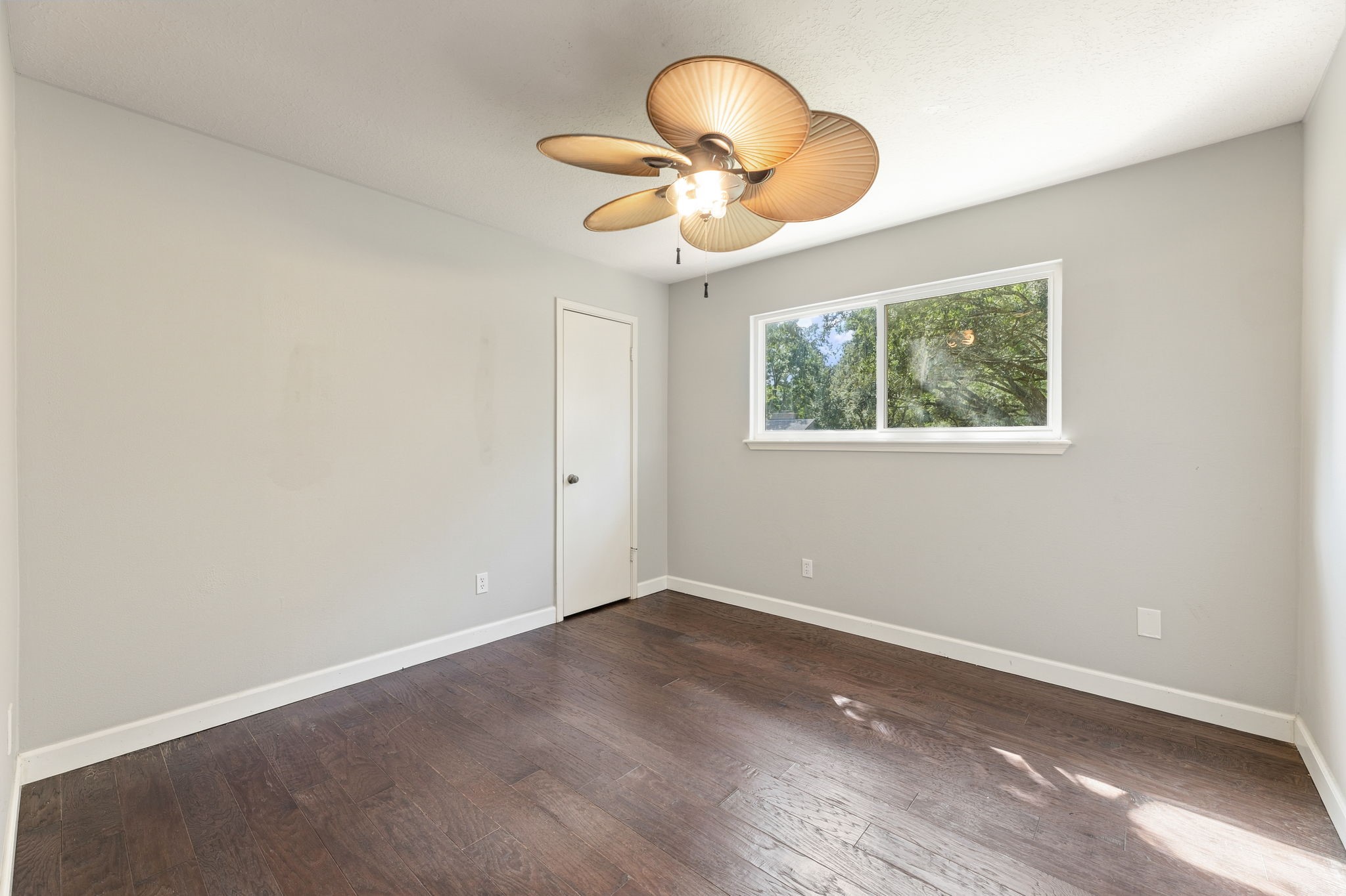 Bright secondary bedroom with wood flooring and ceiling fan!